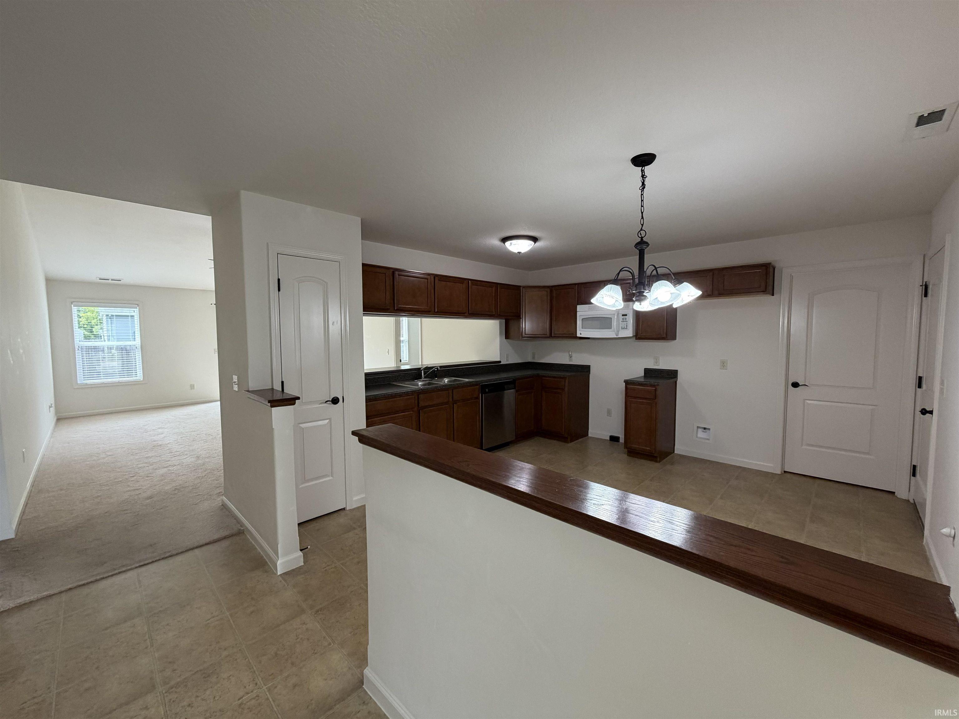 Kitchen featuring dark wood cabinetry, dark countertops, and stainless steel appliances