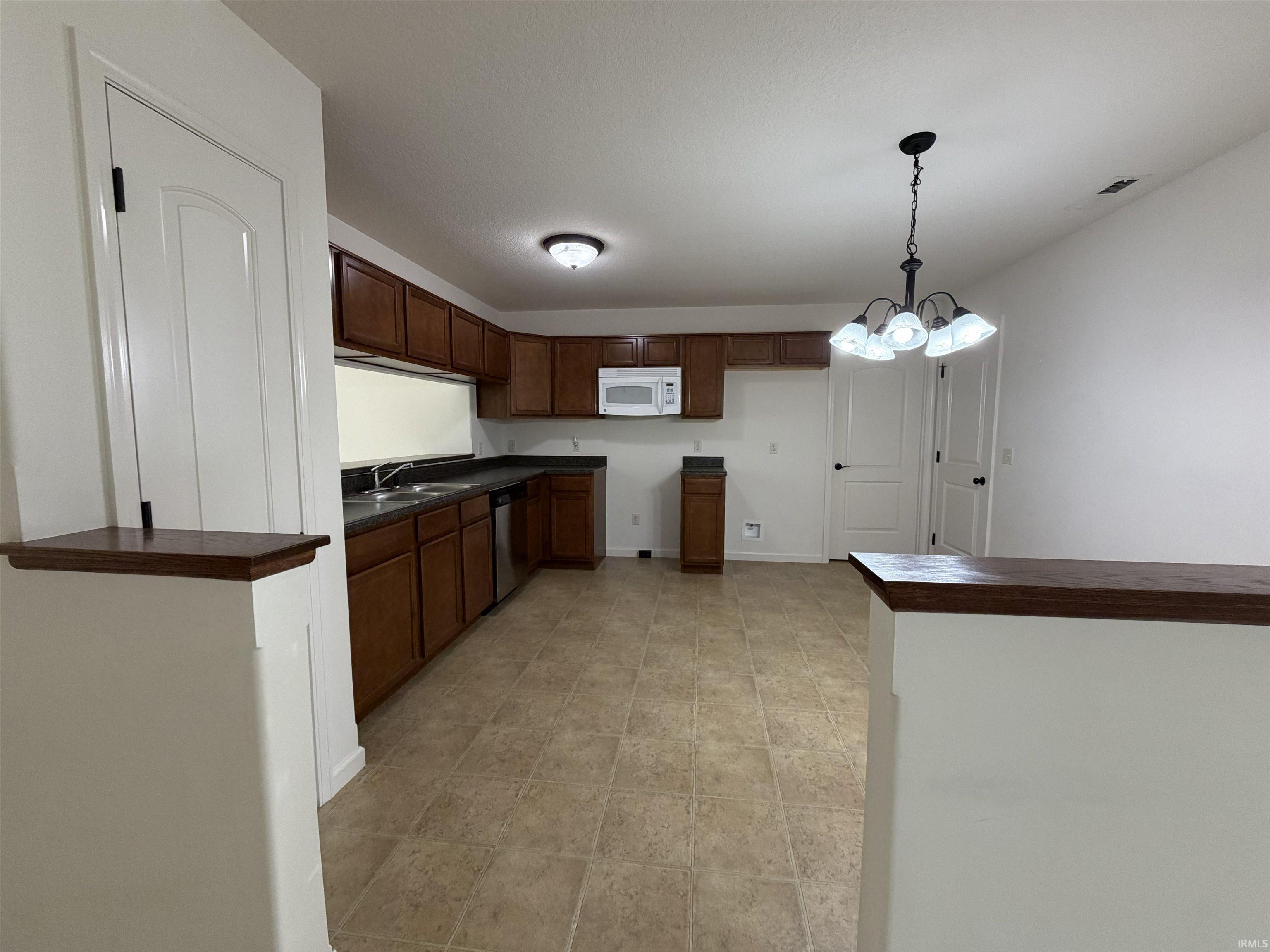 Kitchen featuring wood-finish cabinetry, stainless steel dishwasher, and a built-in microwave
