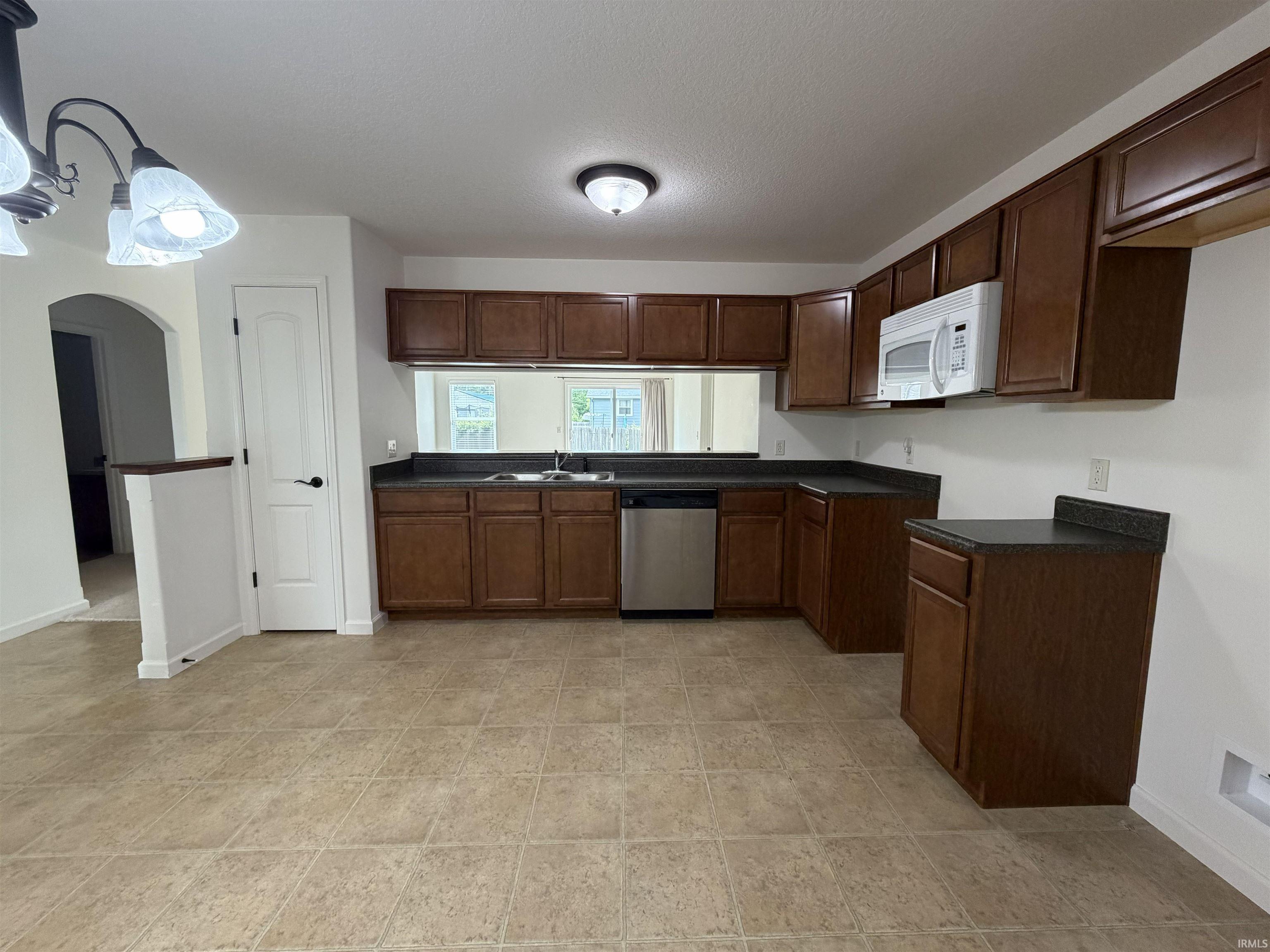 Kitchen featuring wood-finish cabinetry, dark countertops, and a tile floor