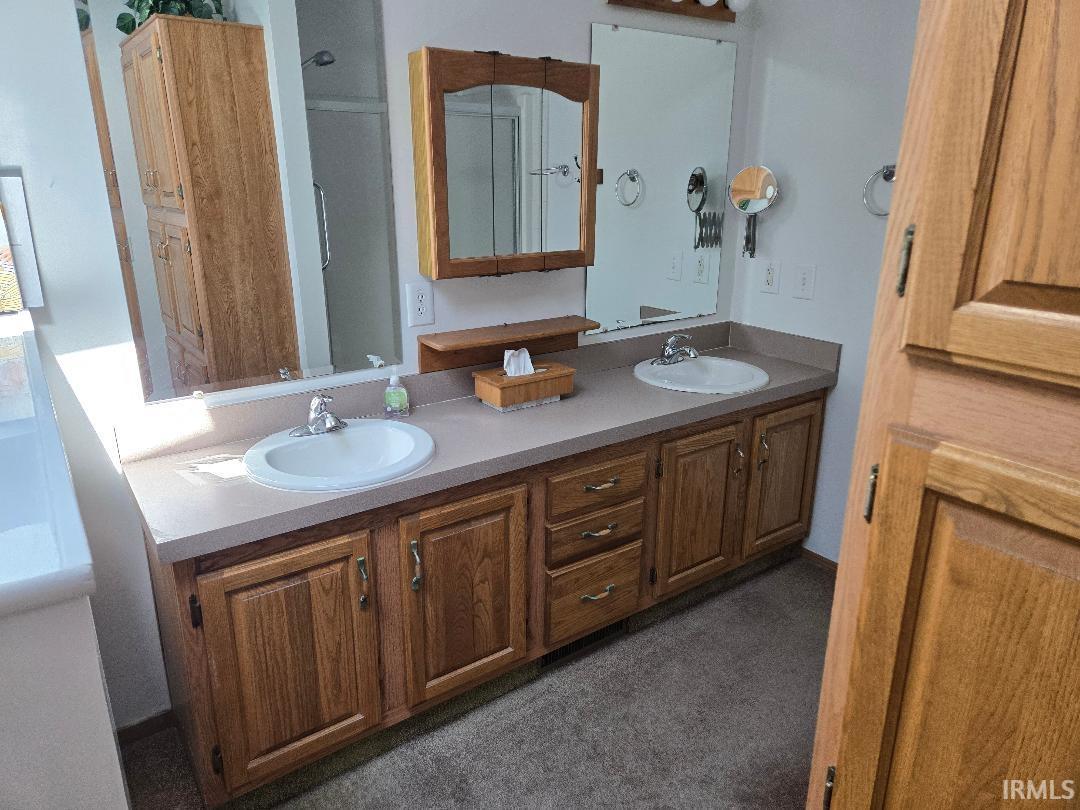 Dual vanity with light wood-finish cabinetry, integrated sinks, and neutral countertops
