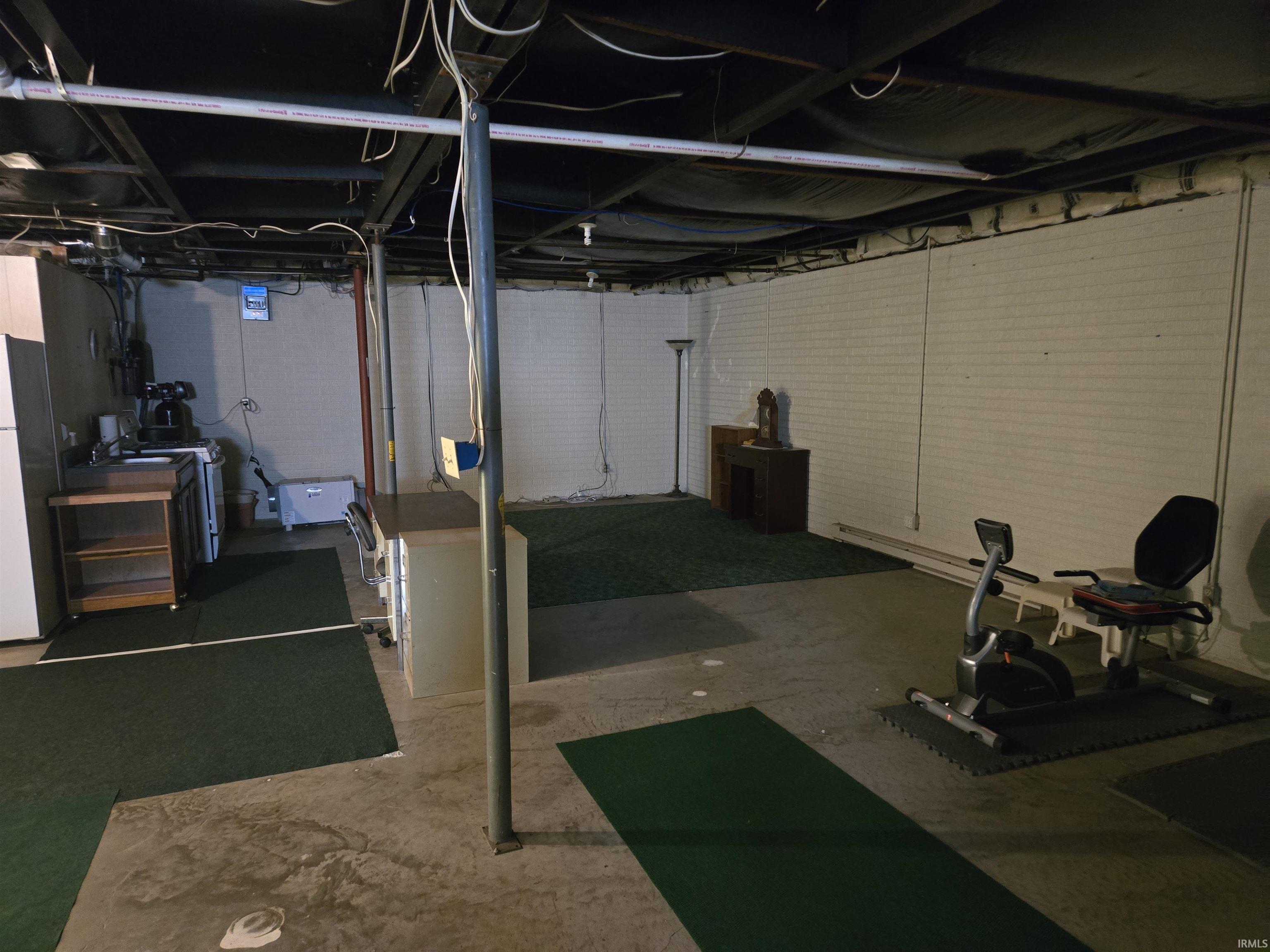 Expansive basement space featuring exposed ceiling joists and brick wall construction