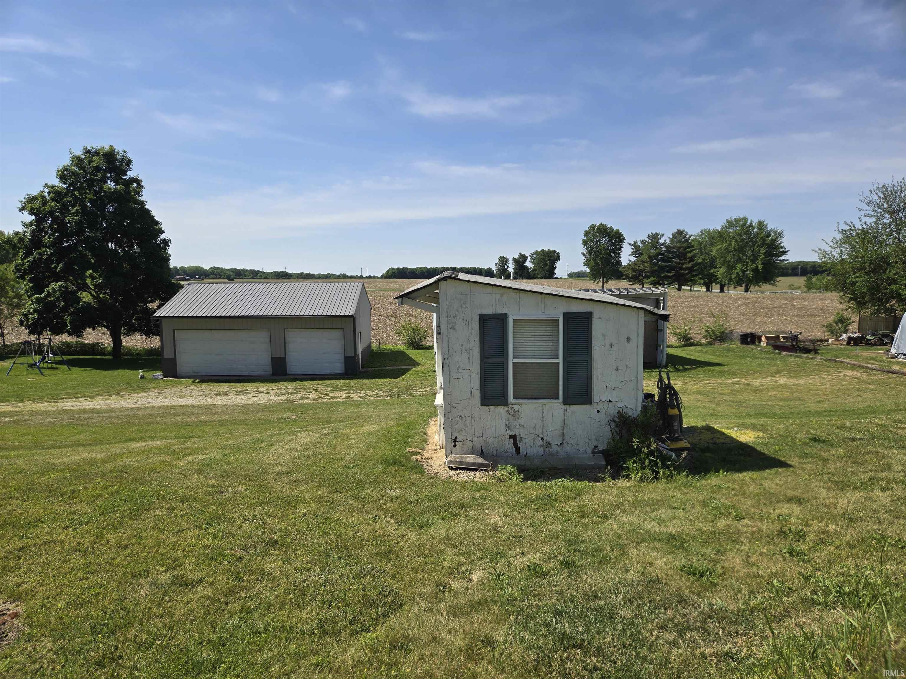 Detached garage with two roll-up doors, a metal roof, and a gravel driveway