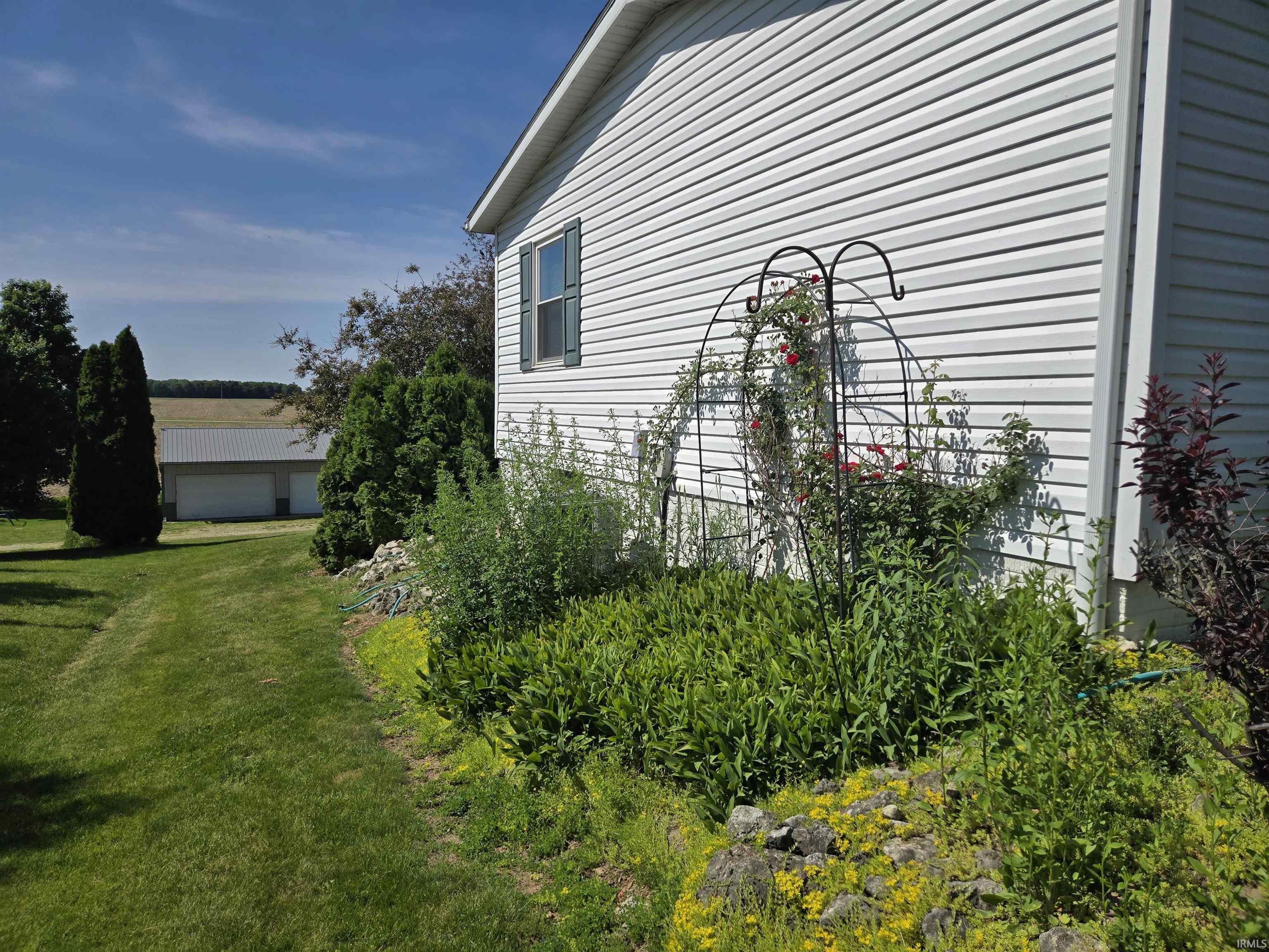 White vinyl siding exterior with a single window featuring dark green shutters