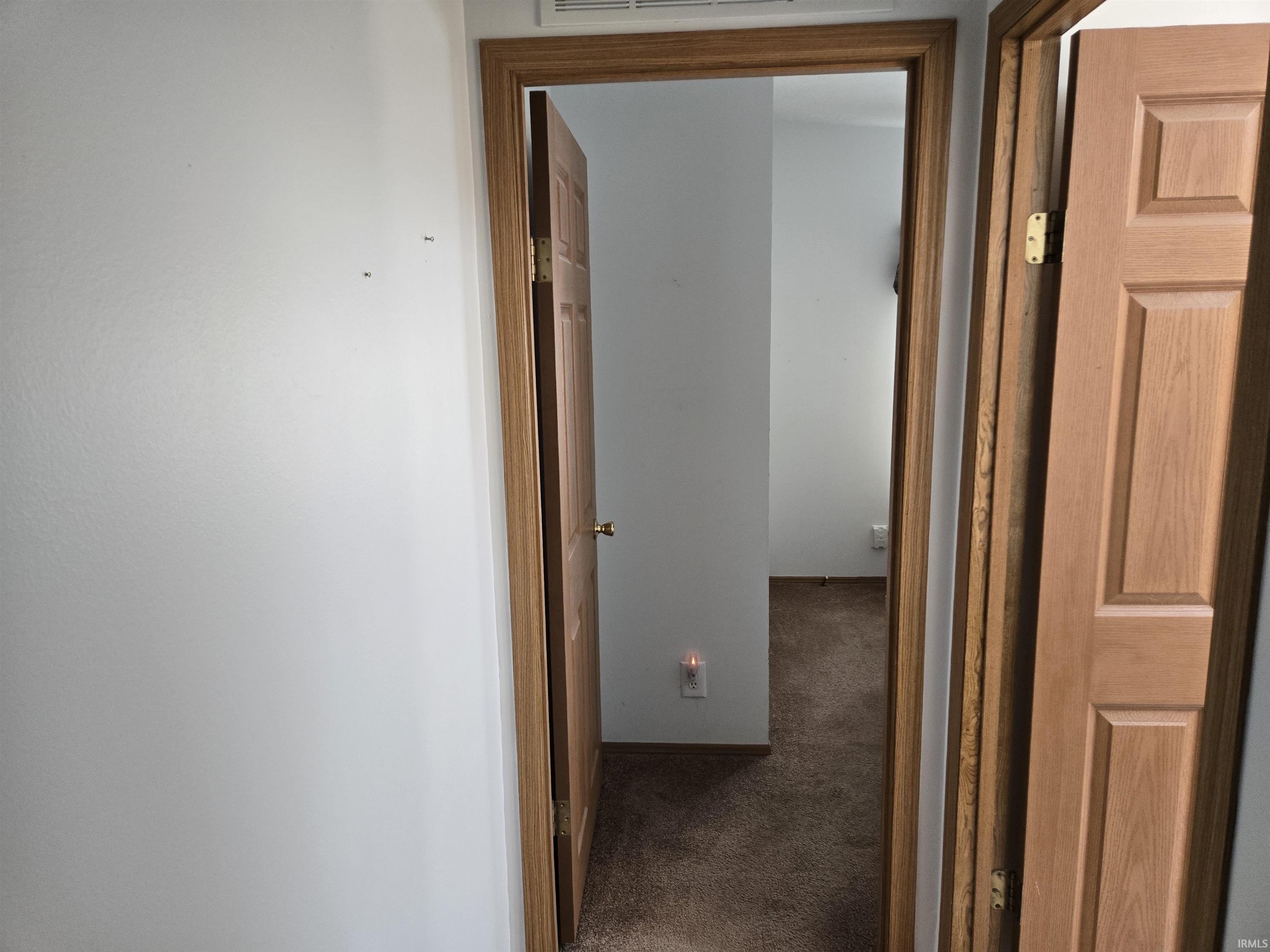 Hallway with neutral wall finish and wood-finish trim and doors