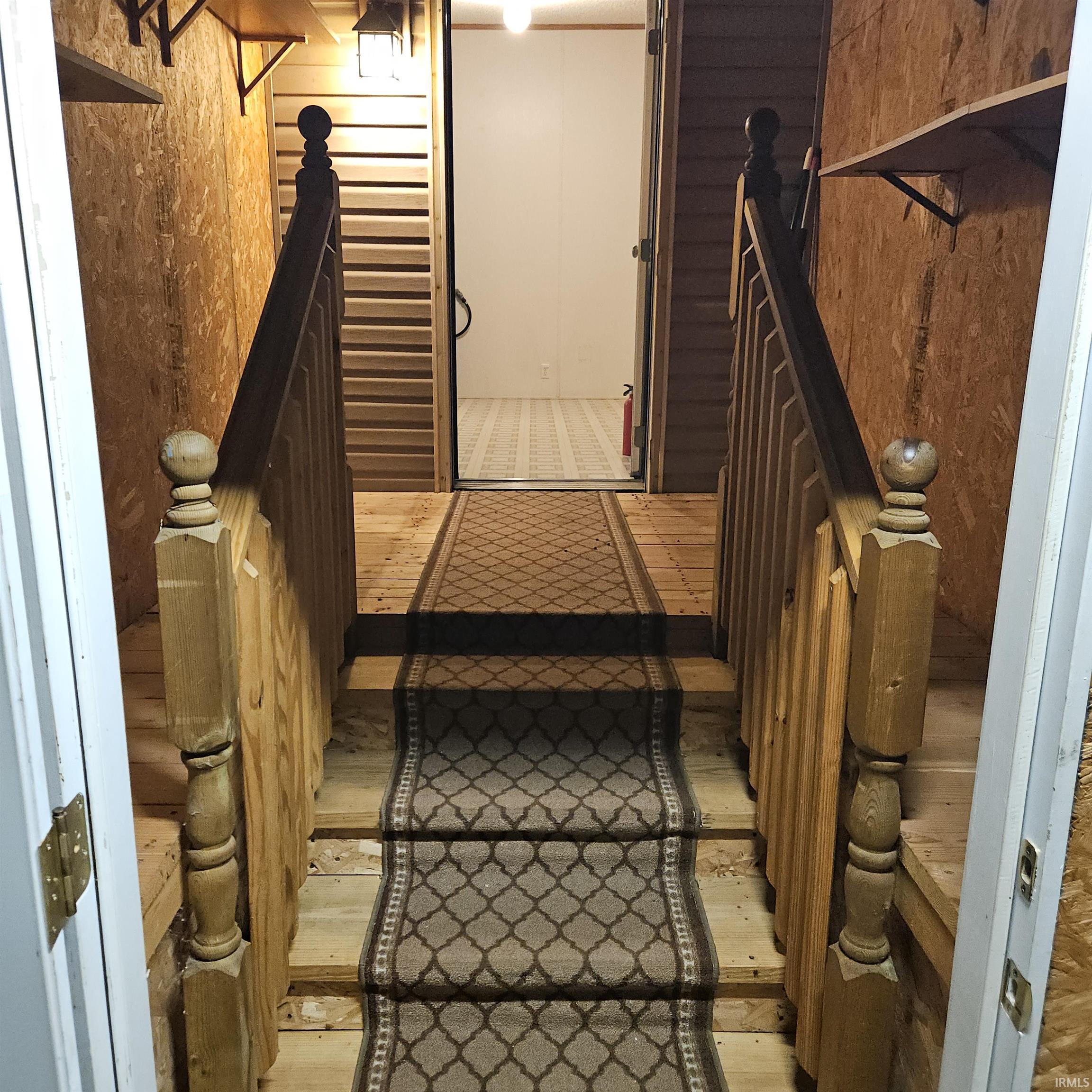Wooden staircase featuring a patterned stair runner and natural wood balusters