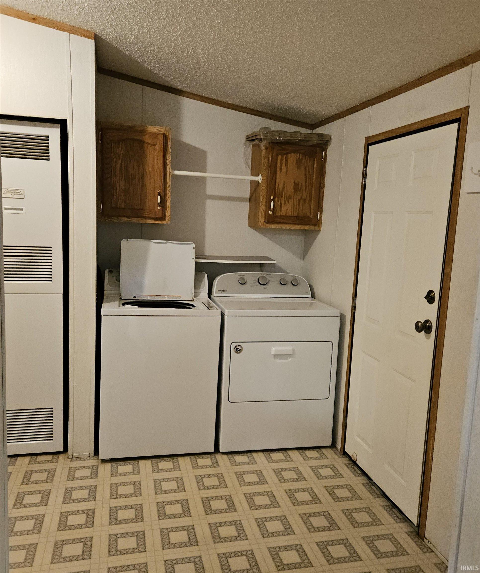 Dedicated utility space featuring patterned linoleum flooring and textured ceiling