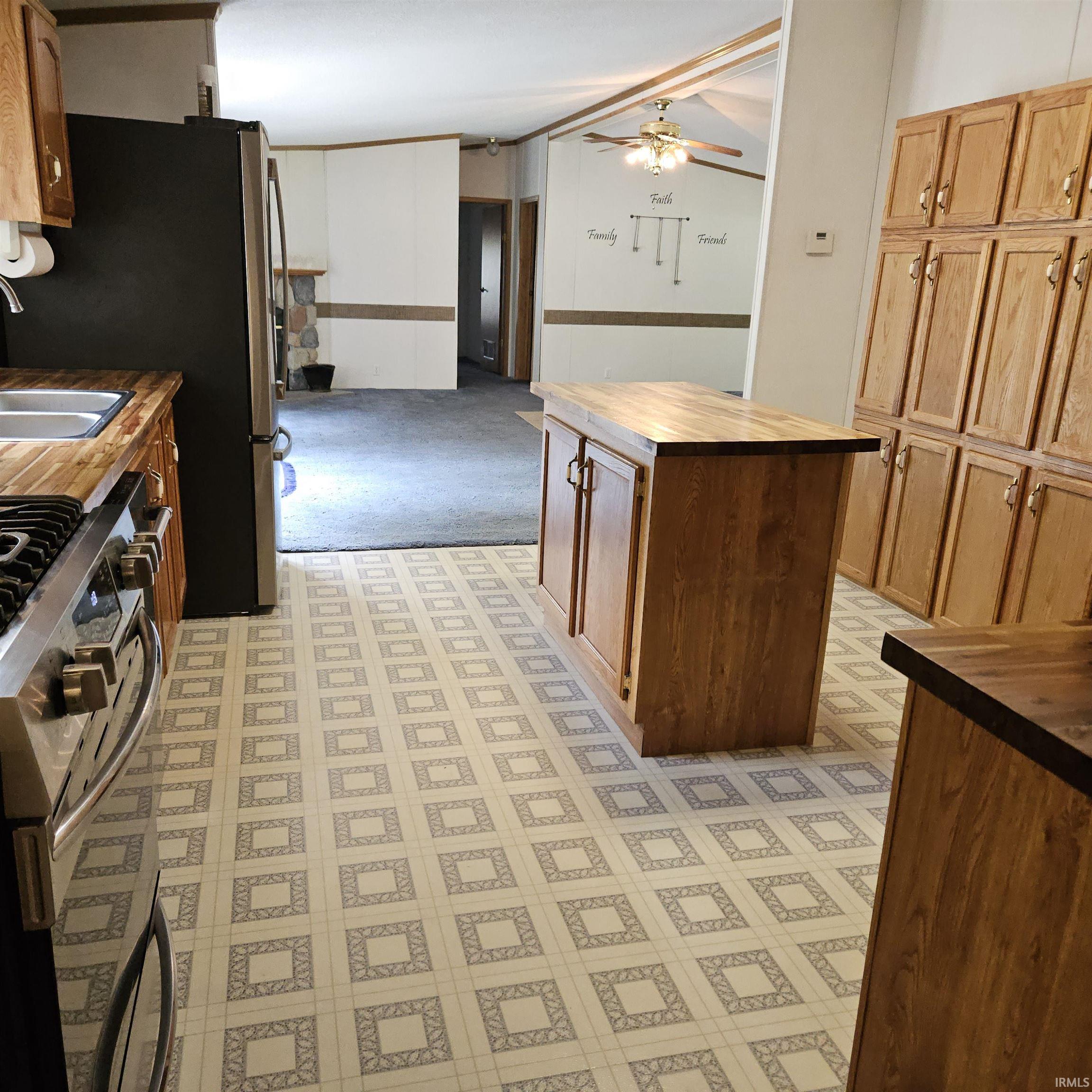 Kitchen featuring extensive wood cabinetry, butcher block countertops, stainless steel appliances, and a central island with storage