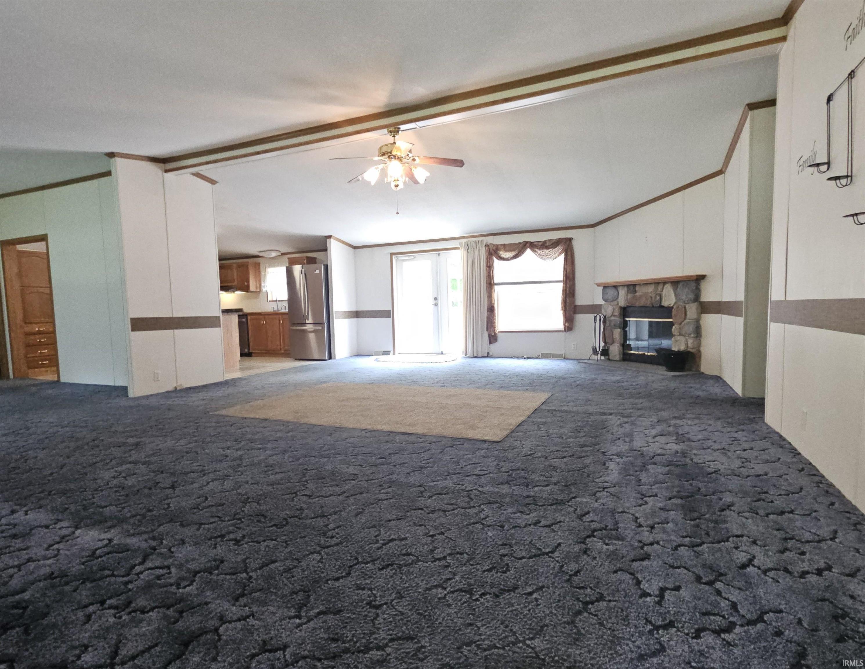Spacious living area featuring a stone-clad fireplace, ceiling fan, and sliding glass door