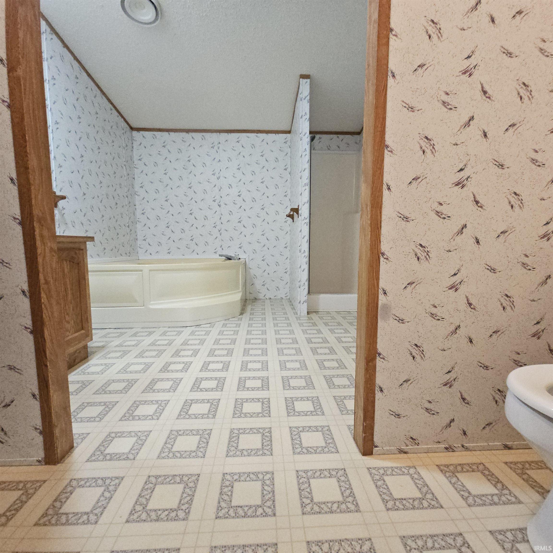 Bathroom featuring a corner soaking tub, a separate shower enclosure, a wood-finish vanity, and patterned vinyl flooring