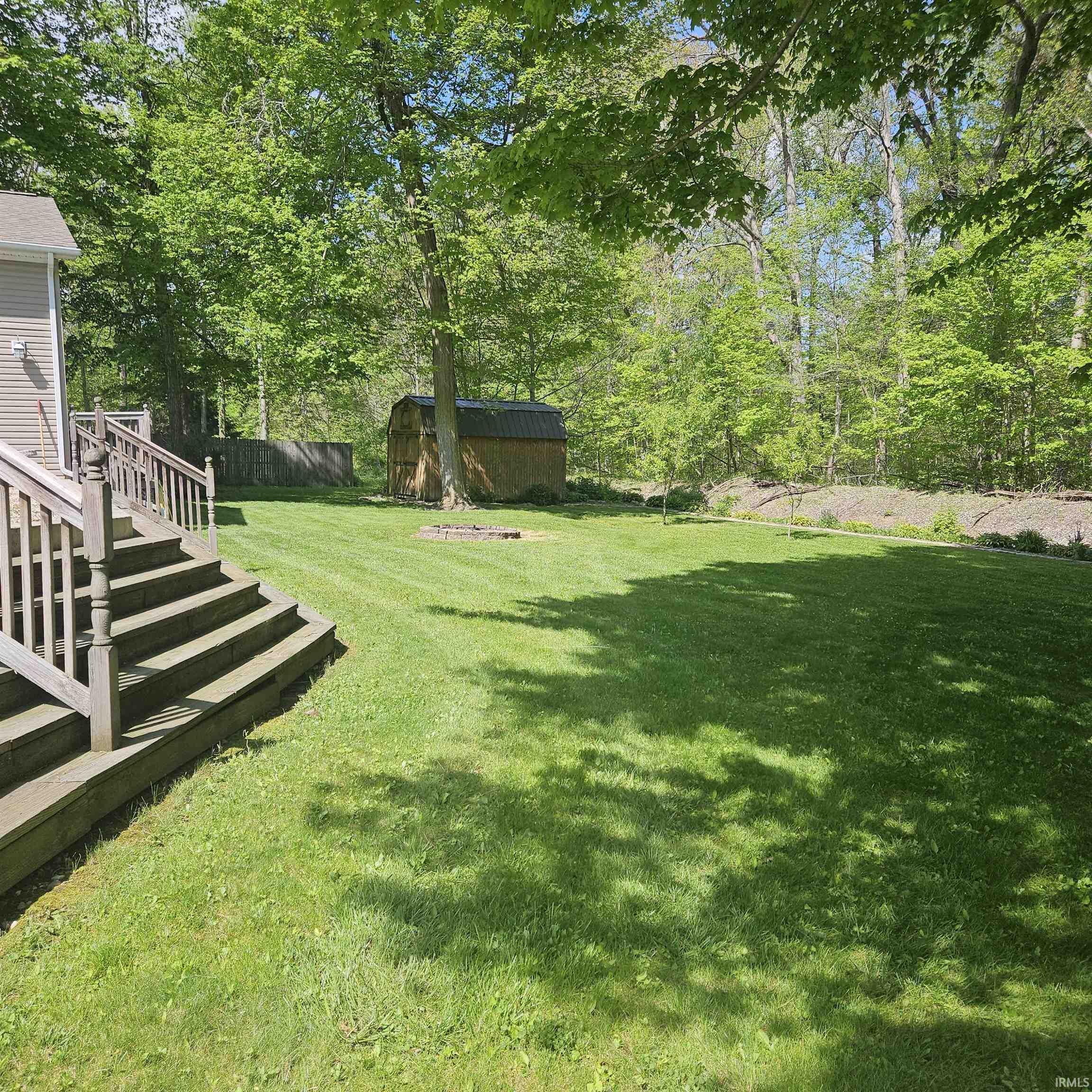Expansive backyard featuring a lush lawn, mature trees, and a wood-sided storage shed