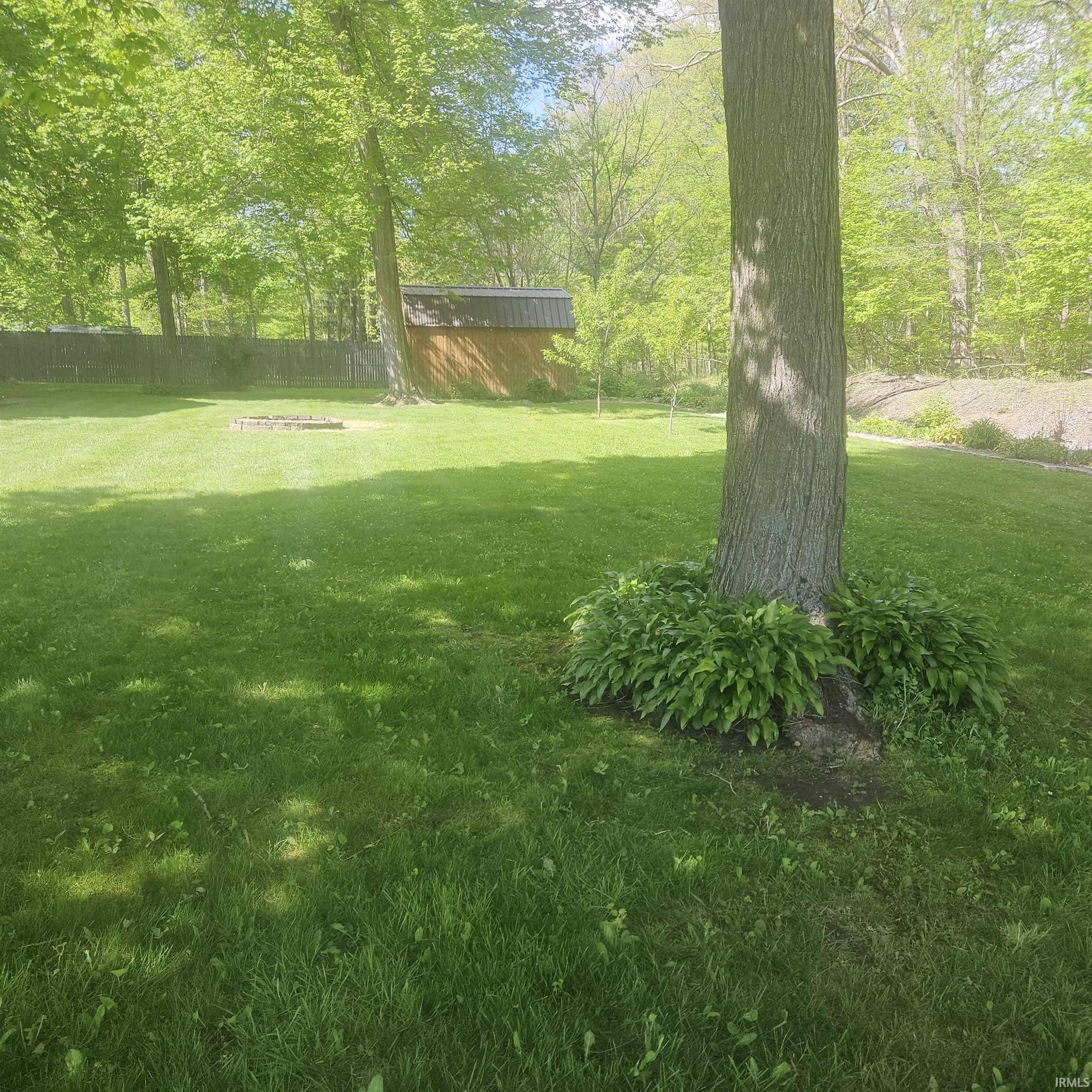 Expansive lawn area featuring mature trees and a wood privacy fence