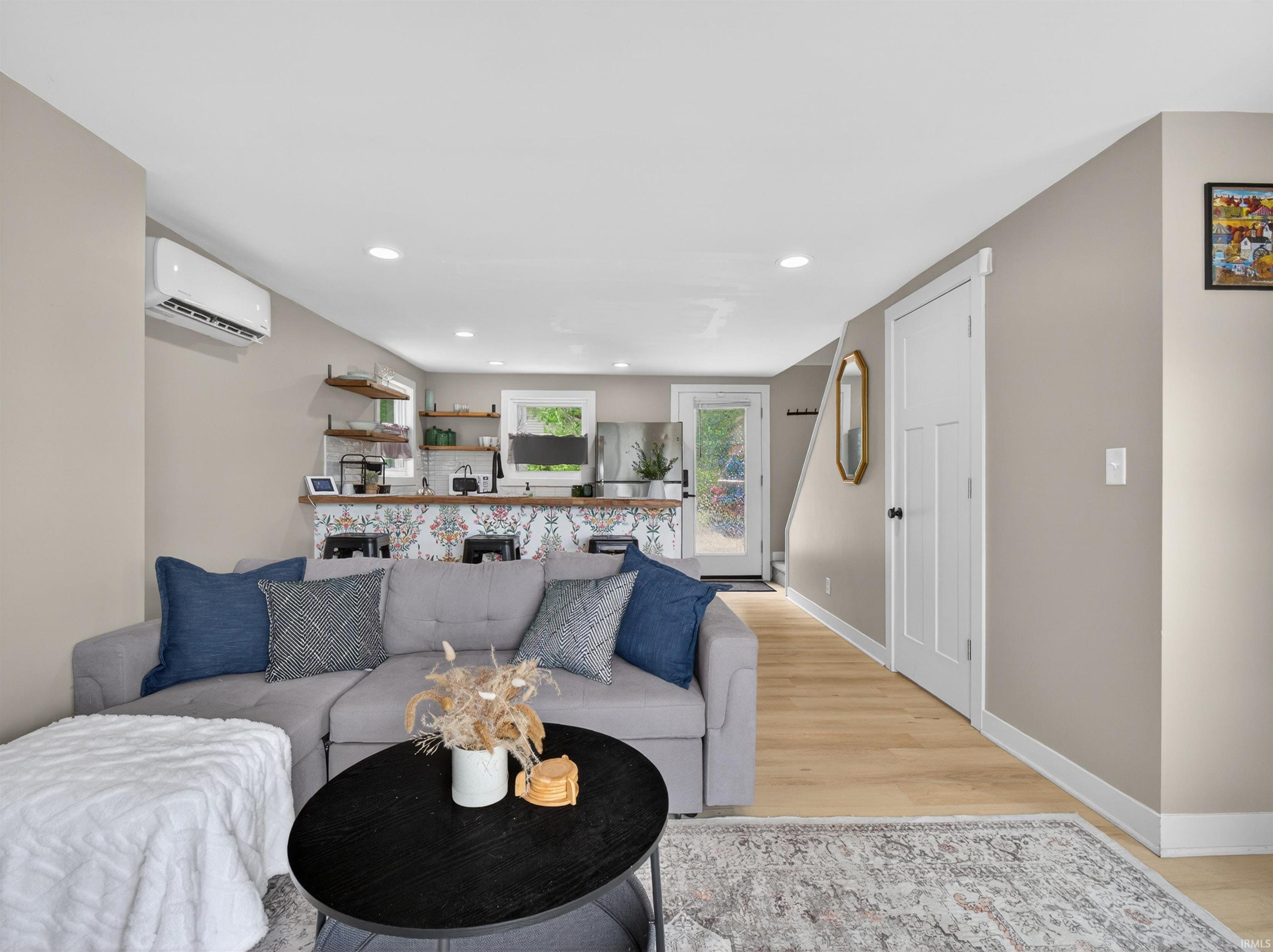 Open-concept living area with wood-finish flooring, recessed lighting, and a white interior door