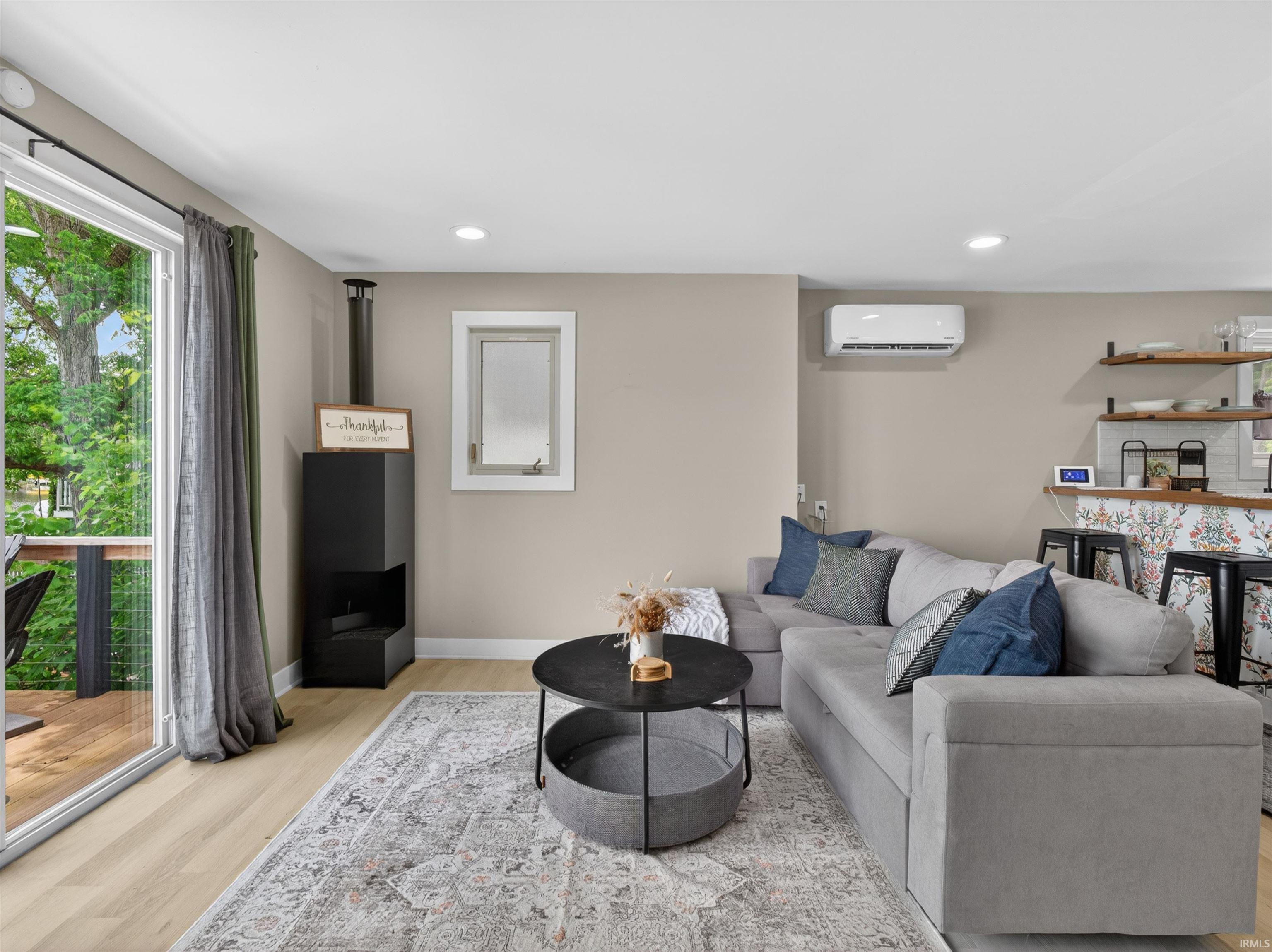 Living area featuring wood-finish flooring, recessed lighting, and a black freestanding fireplace