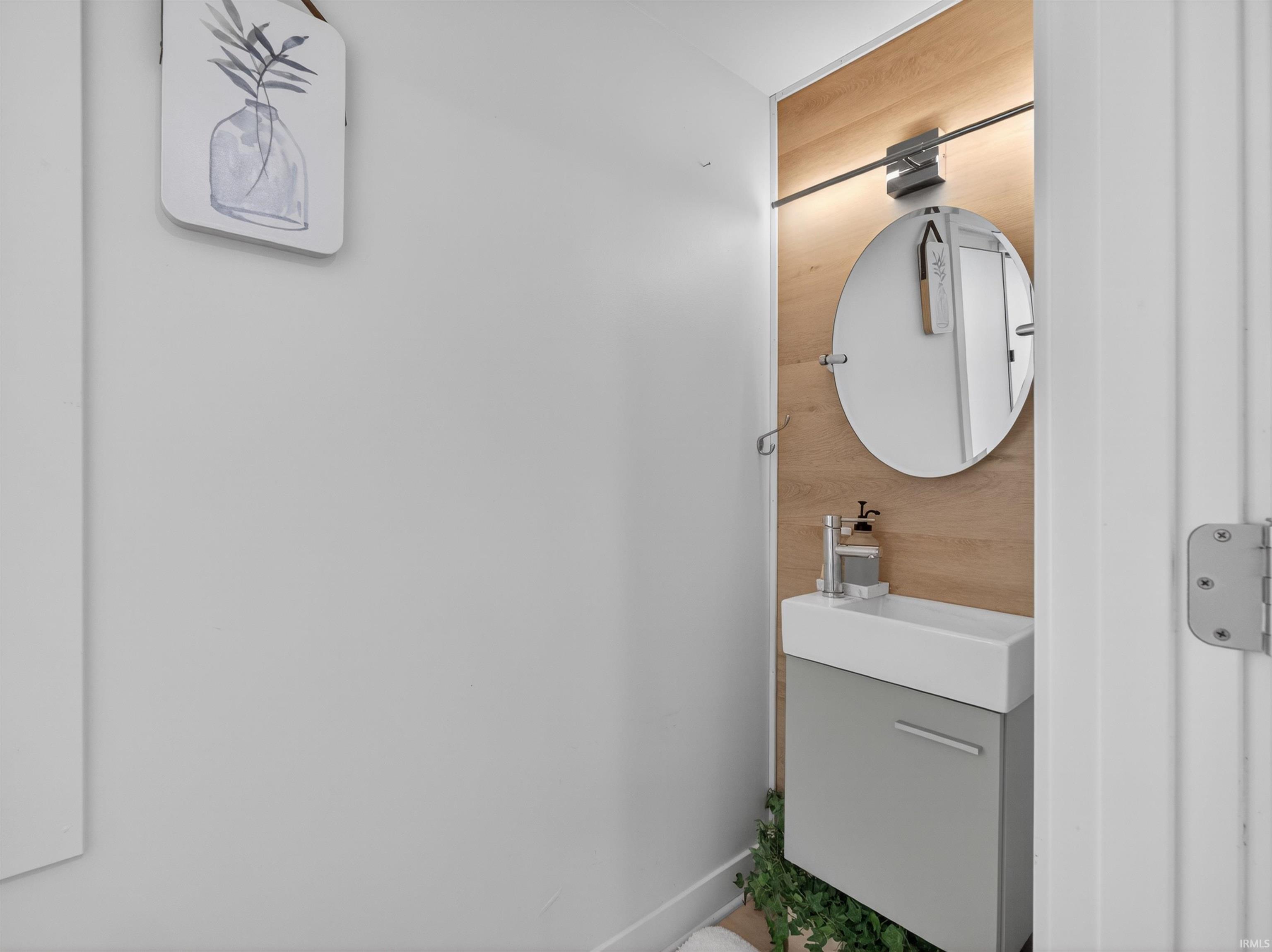 Compact bathroom vanity featuring a rectangular vessel sink, gray cabinetry, and a circular mirror
