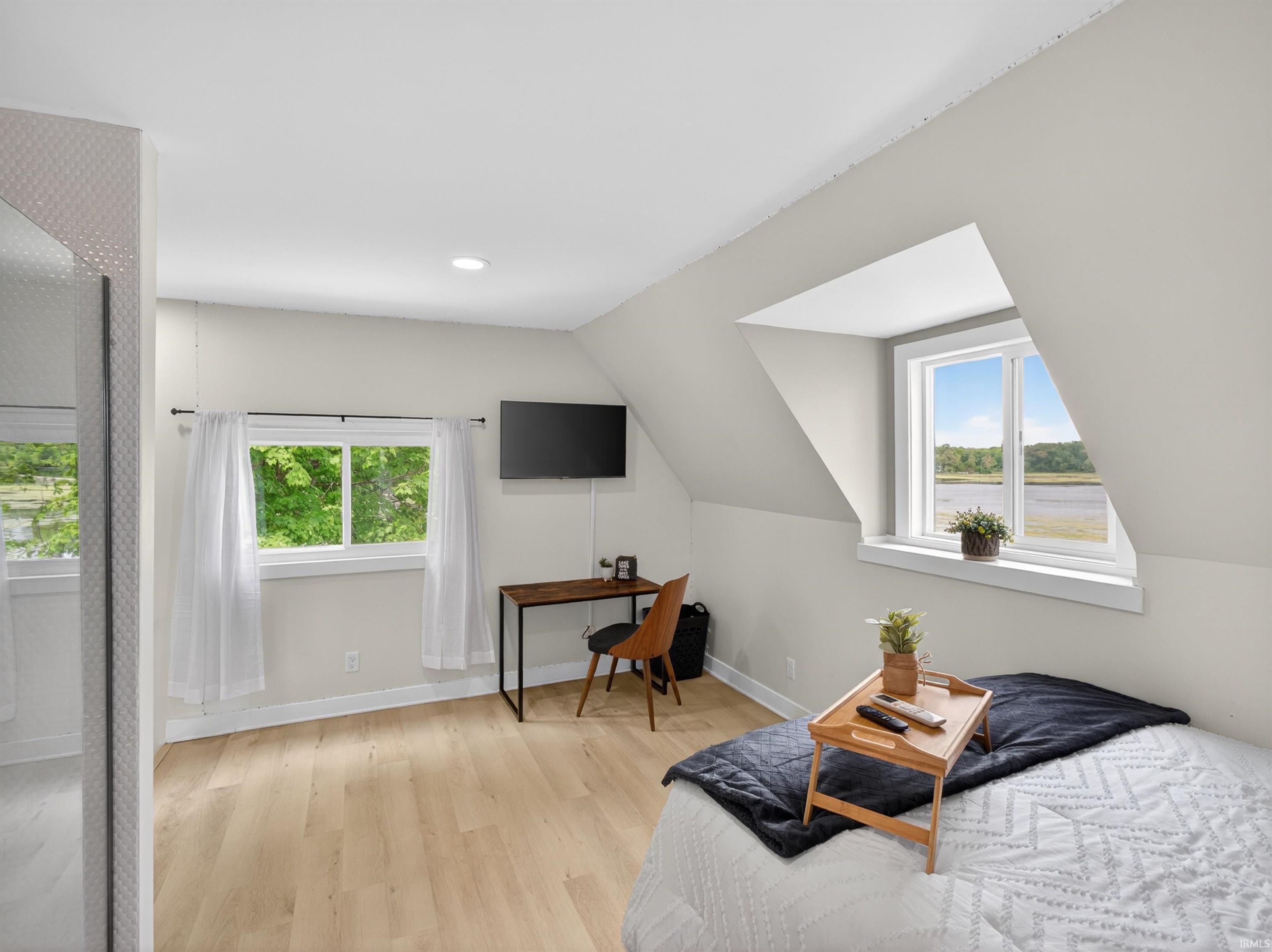 Bright room featuring light wood-finish flooring, recessed lighting, and multiple windows