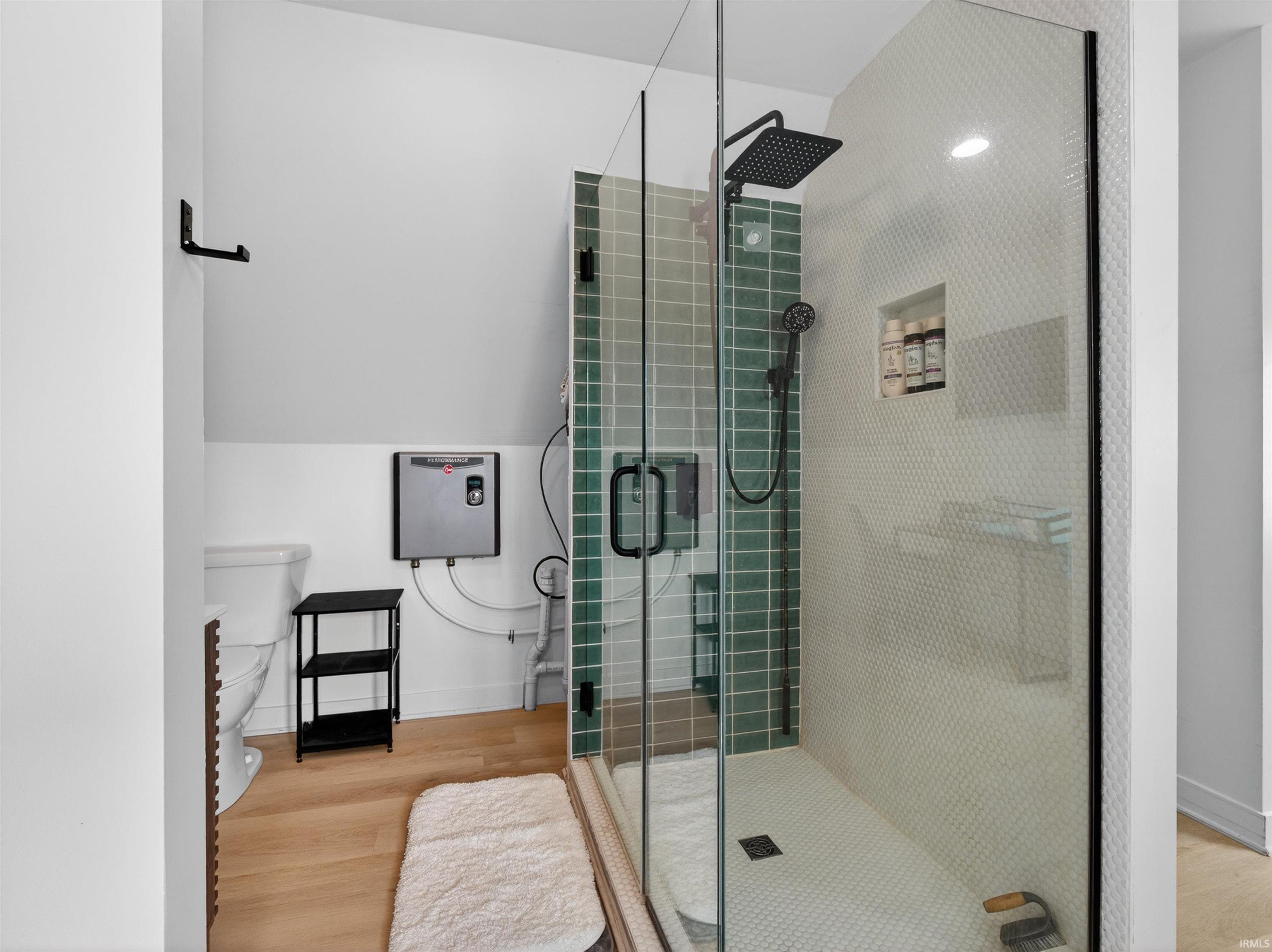 Glass-enclosed shower featuring green subway tile and a matte black rainfall showerhead