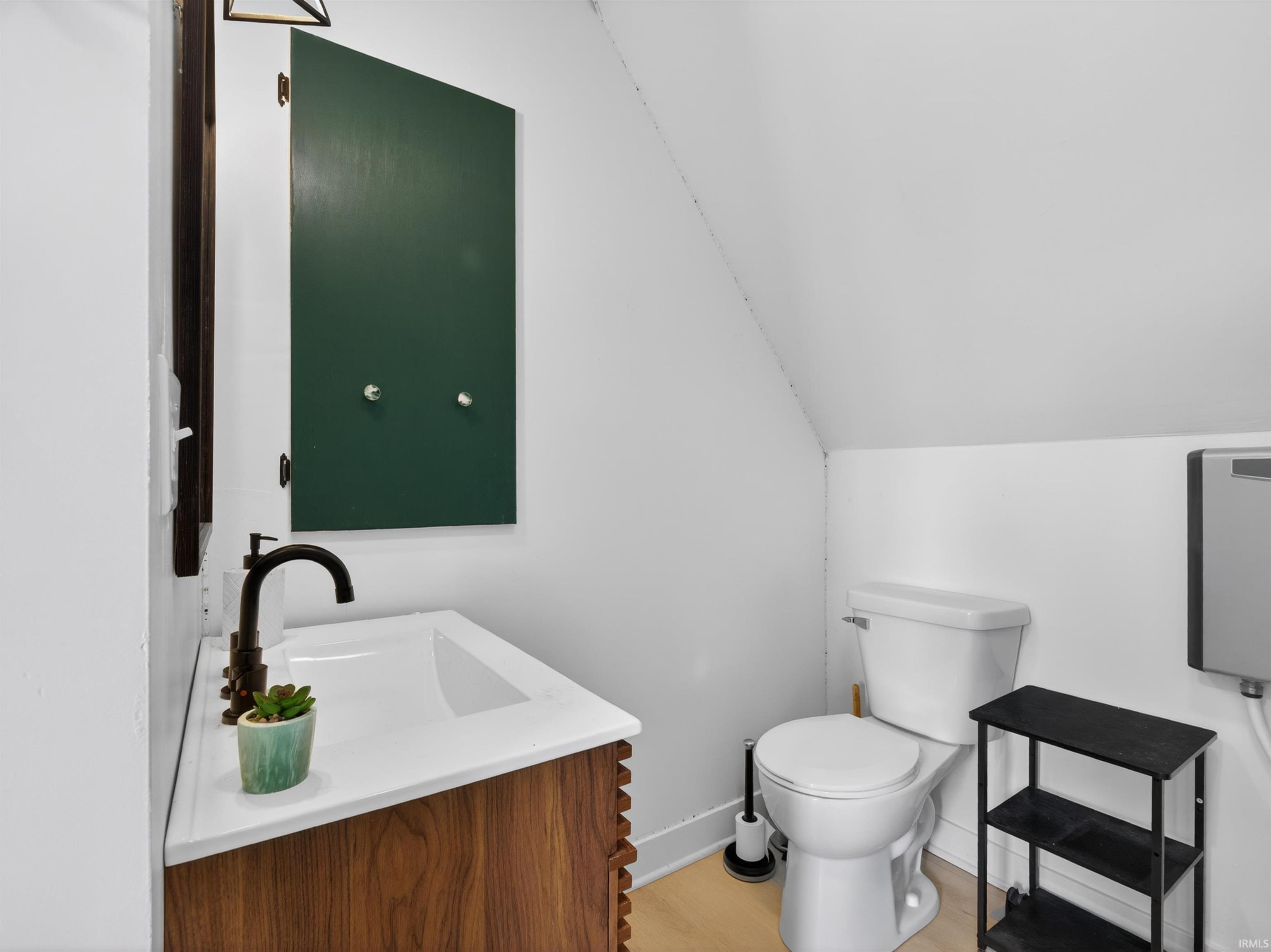 Bathroom featuring a wood-finish vanity with an integrated white sink, dark bronze faucet, and a dark green medicine cabinet