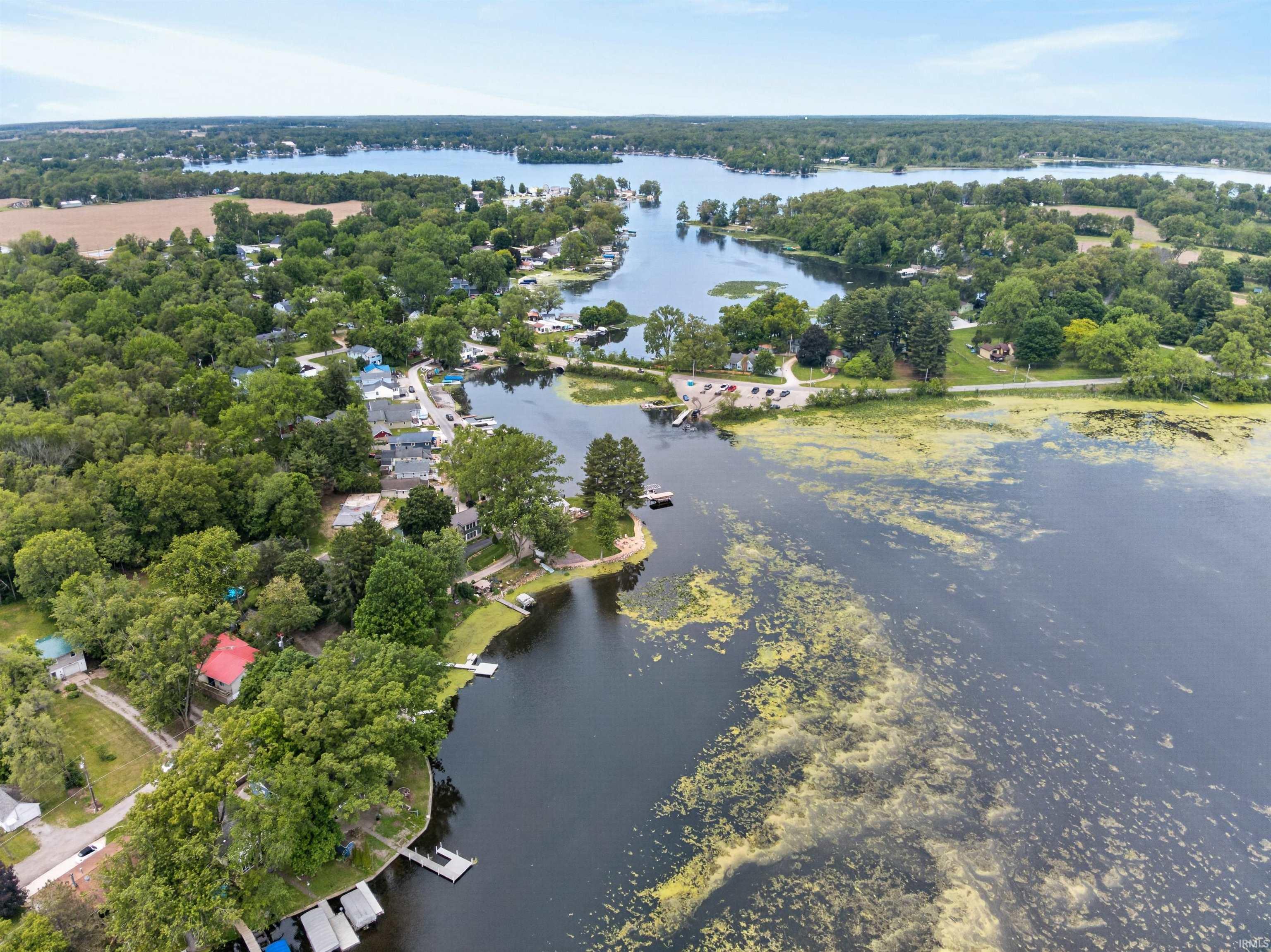 Expansive aerial perspective showcasing a lakefront community with multiple bodies of water surrounded by abundant mature trees and residential properties