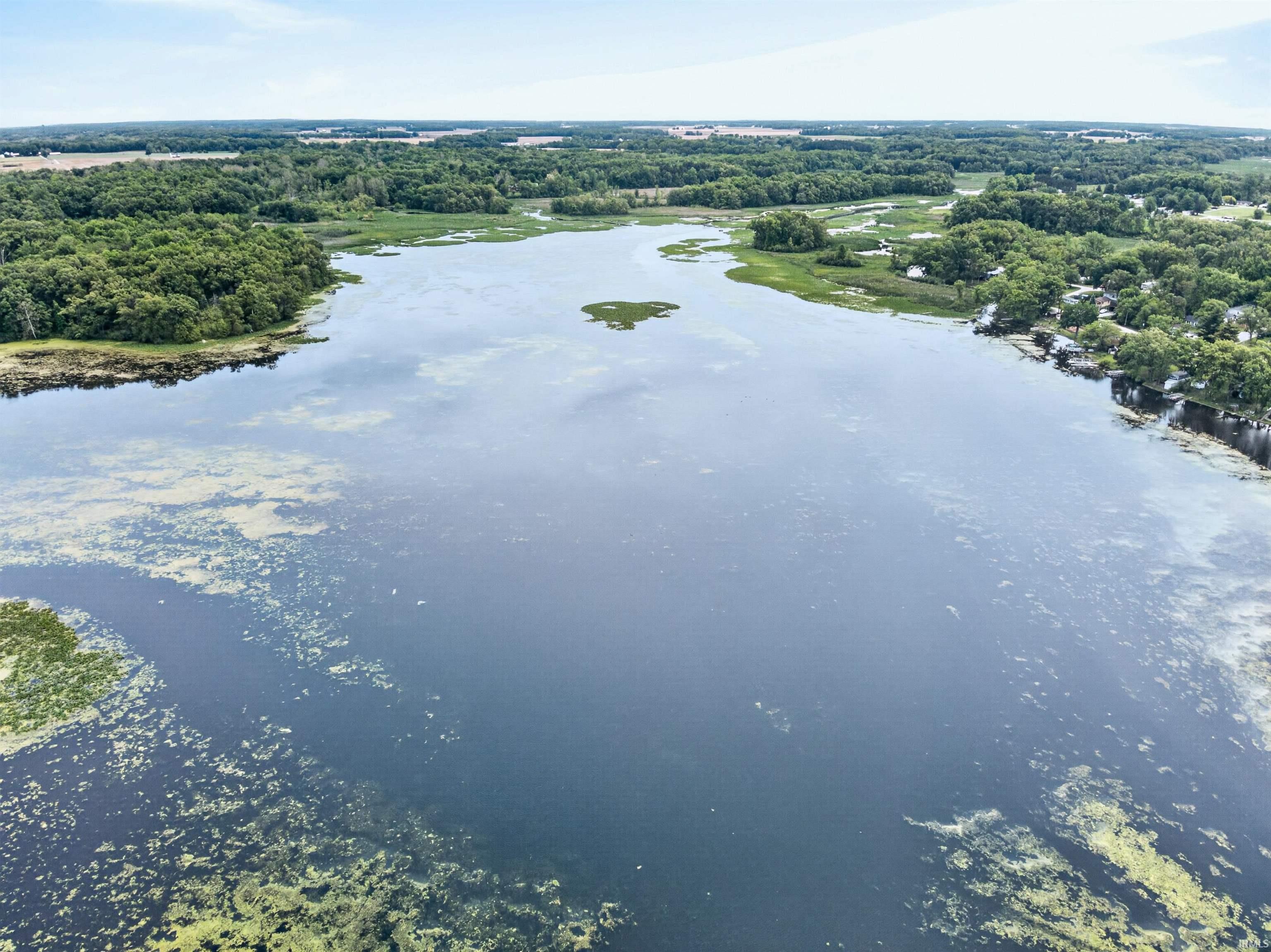 Expansive lake with varied shoreline vegetation and surrounding wooded areas