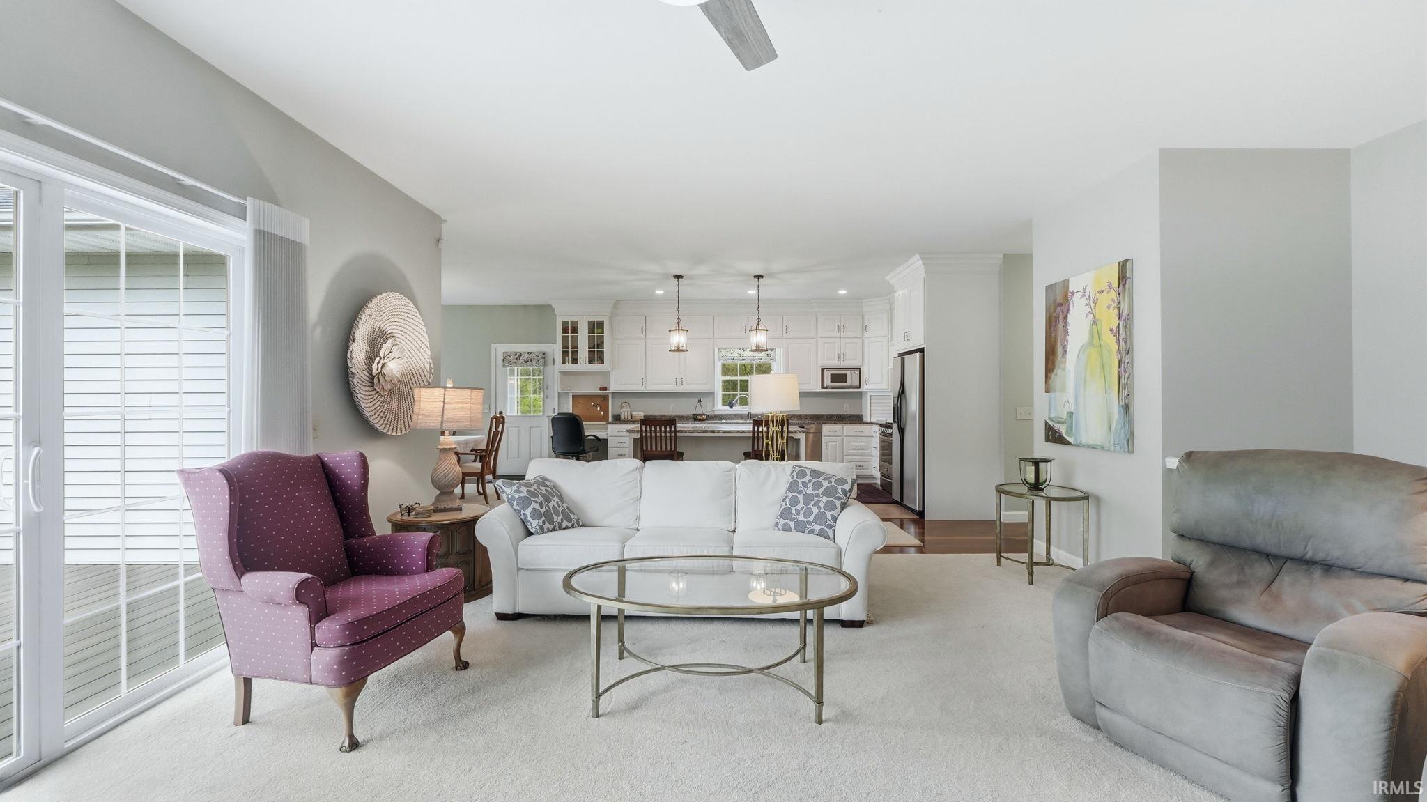 Open-concept living area with light-colored walls and carpet flooring