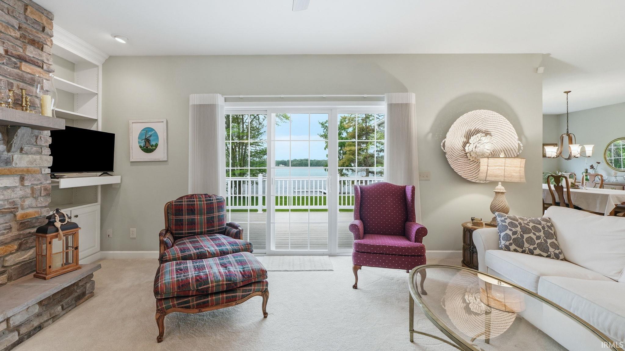 Living space featuring a stone-clad fireplace with built-in shelving, sliding glass doors, and light-colored carpeting