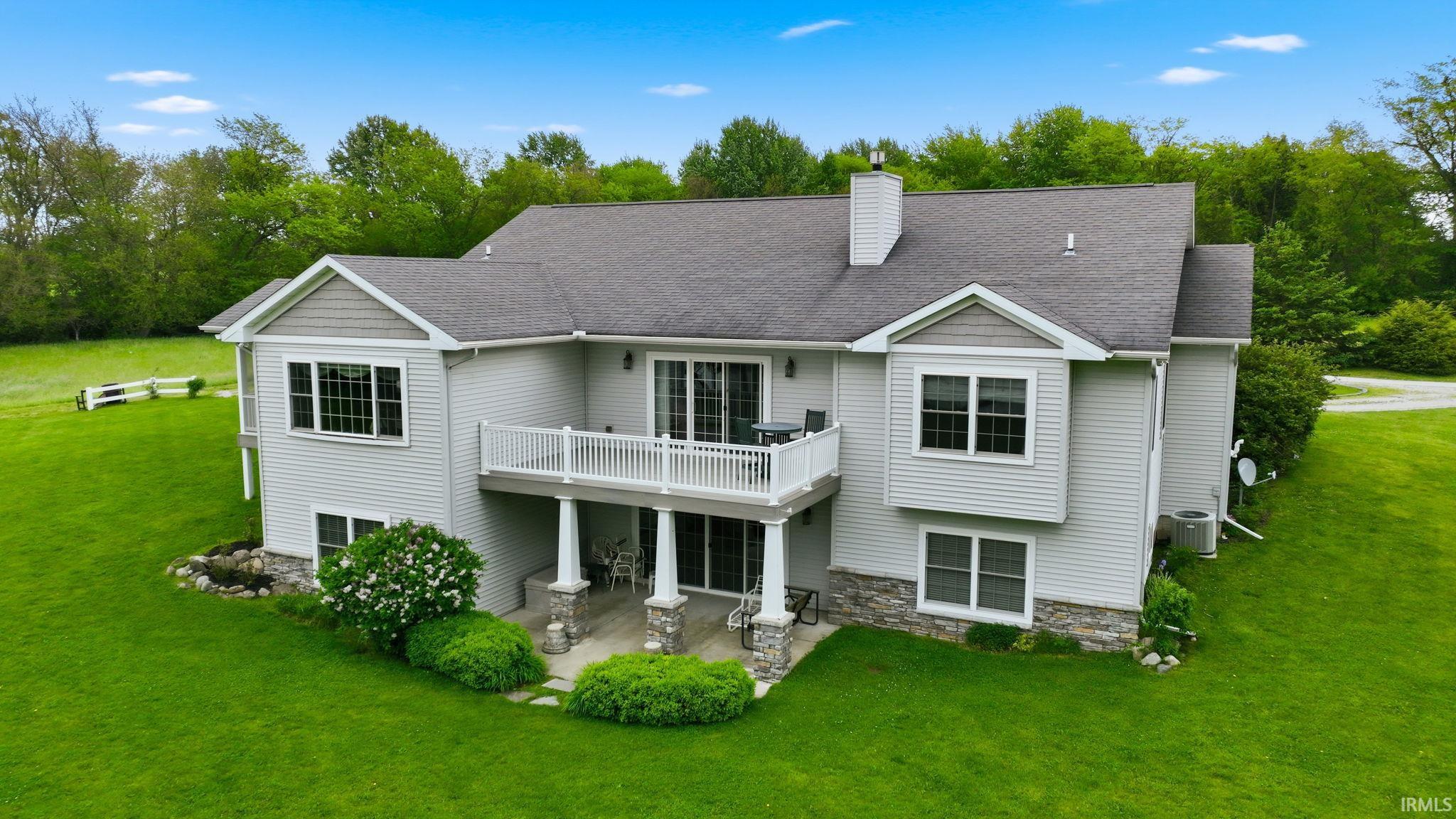 Rear exterior featuring light gray siding, dark gray shingle roof, and stone facade accents