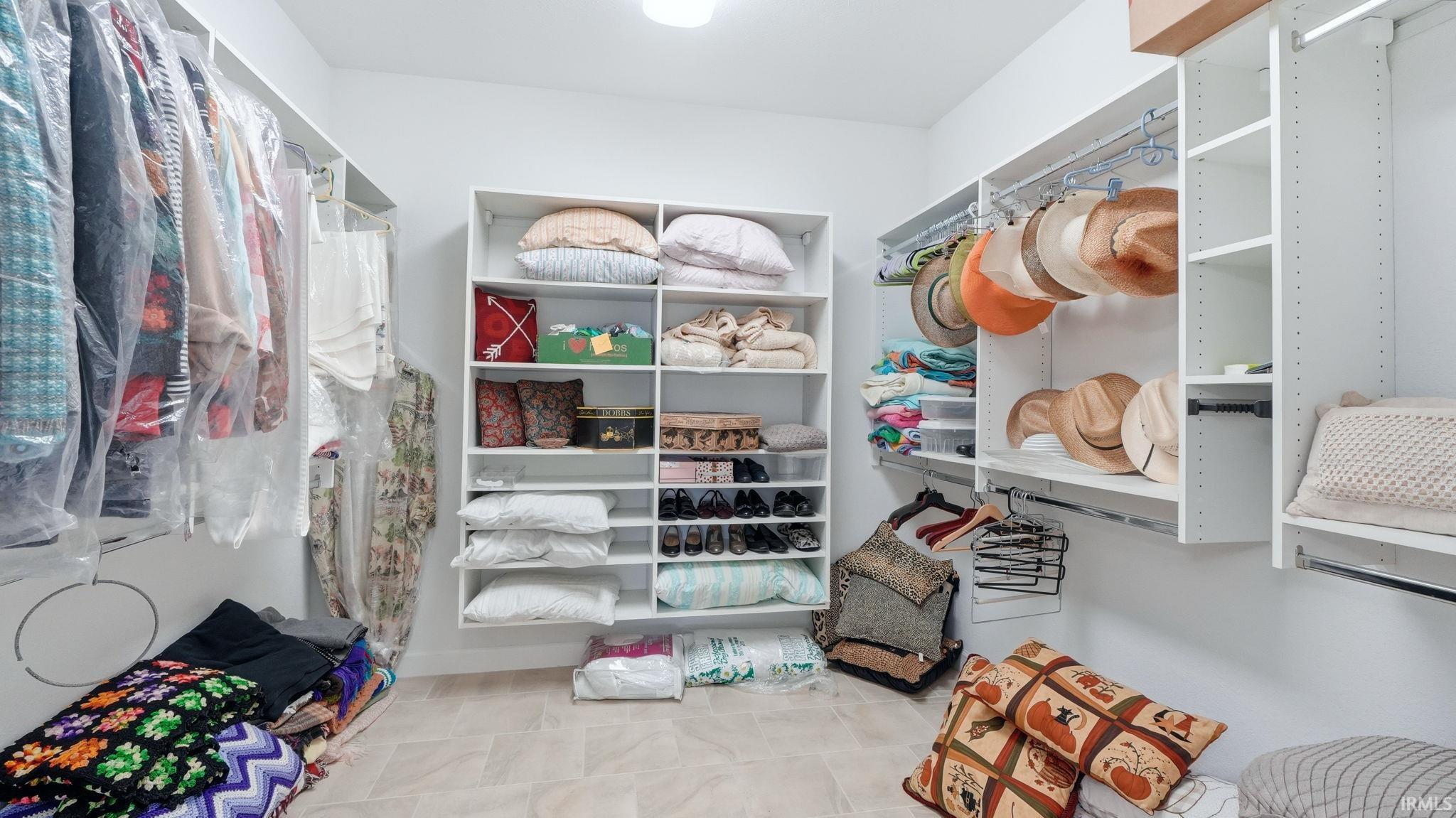 Spacious walk-in closet featuring custom shelving units, integrated hanging rods, and light-toned flooring