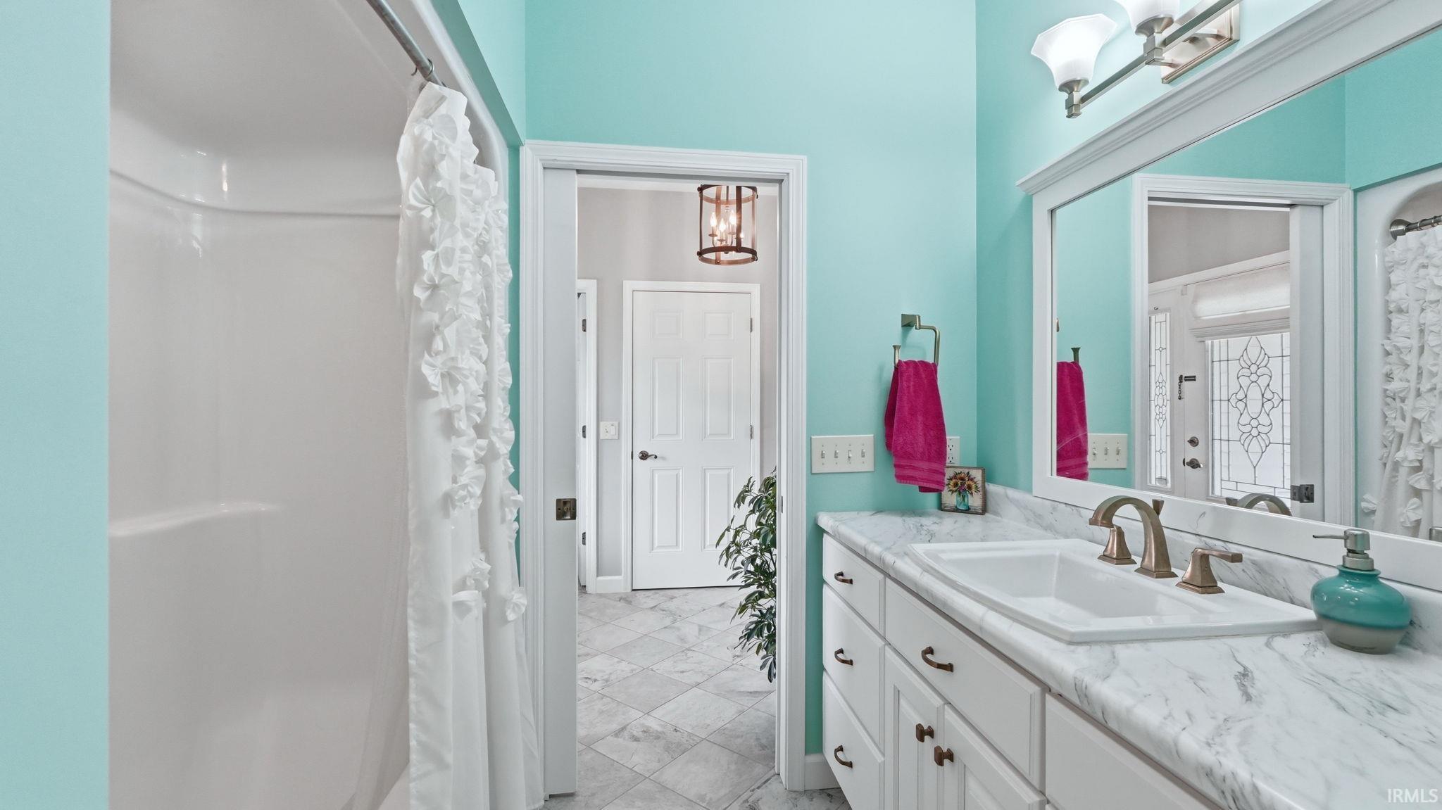 Bathroom featuring a single vanity with a solid surface countertop, an undermount sink, and a brushed bronze faucet