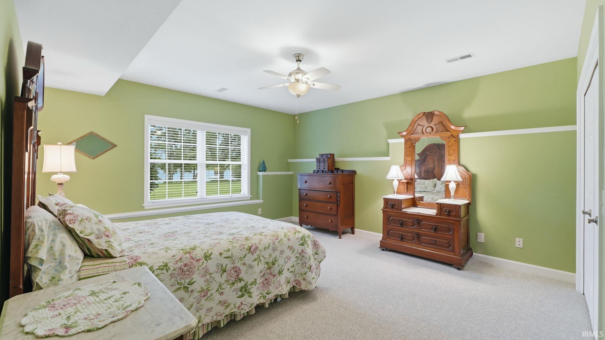 Carpeted room featuring a white ceiling fan, a large window with white blinds, and light green walls with white trim