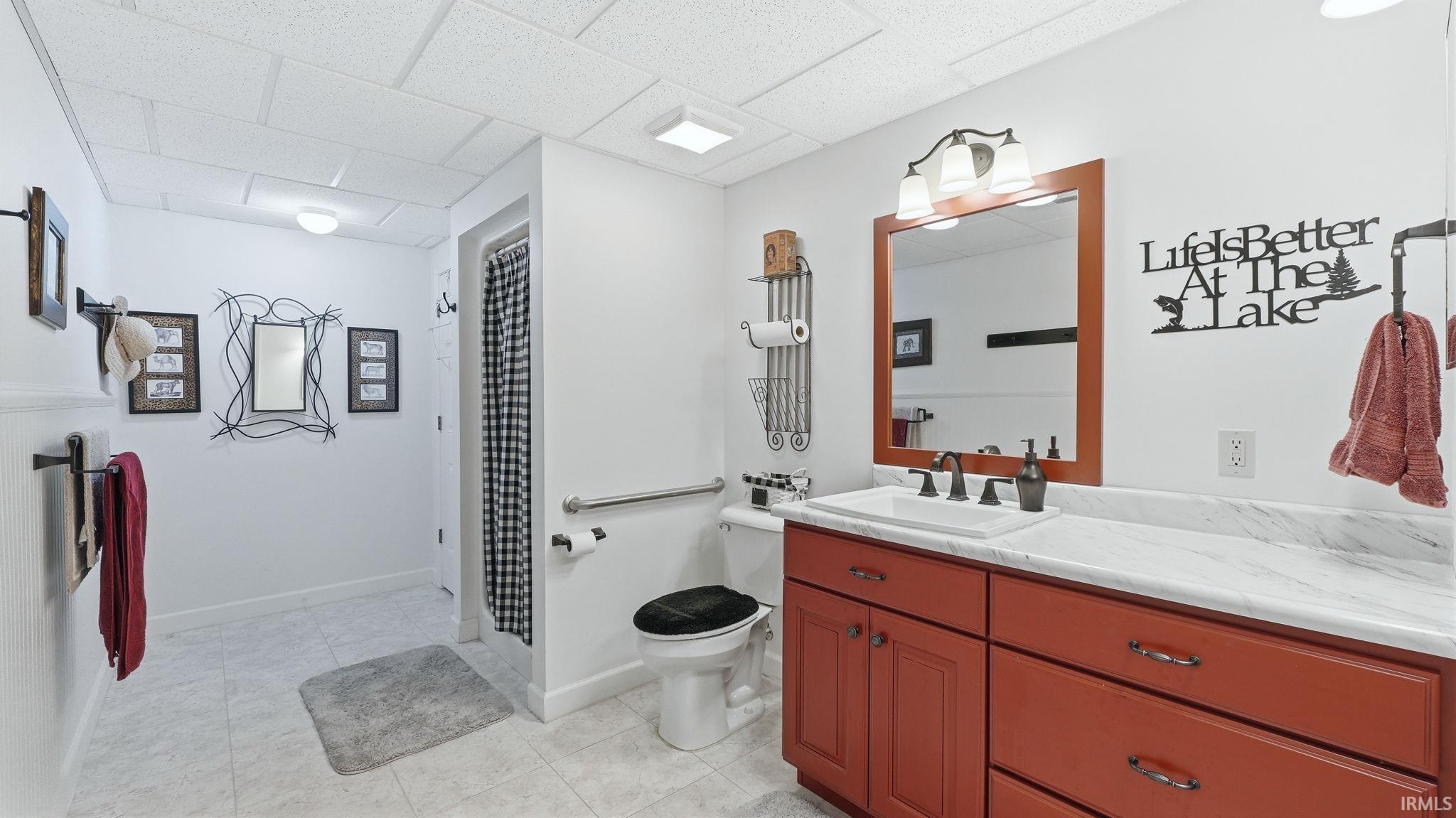 Bathroom with a deep orange vanity featuring a white marble-finish countertop and a rectangular undermount sink