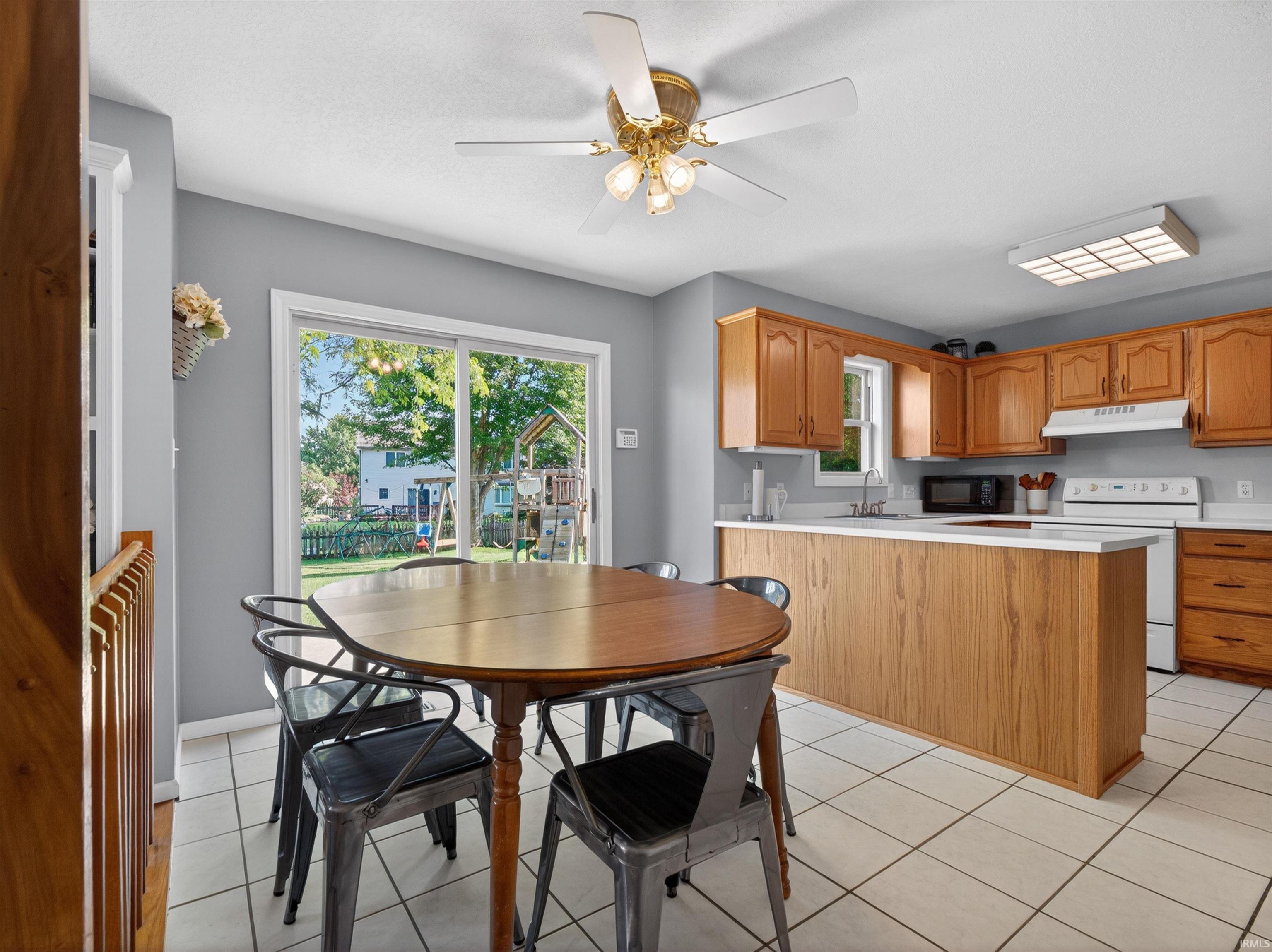 Kitchen featuring light wood cabinetry, white appliances, and a peninsula with countertop seating