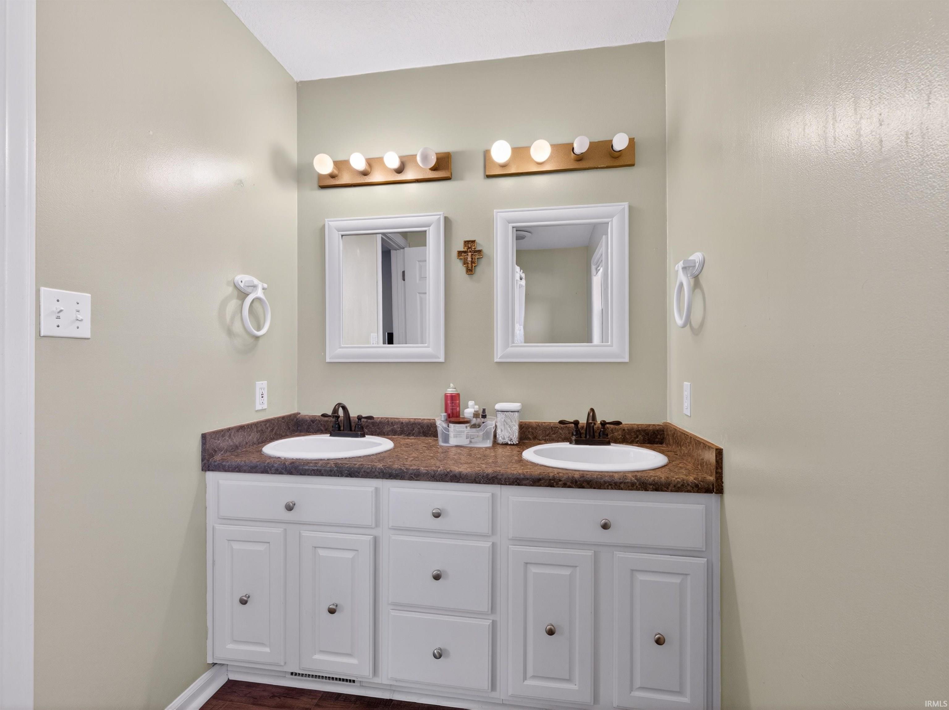 Double vanity with integrated sinks, brown countertop, and white cabinetry