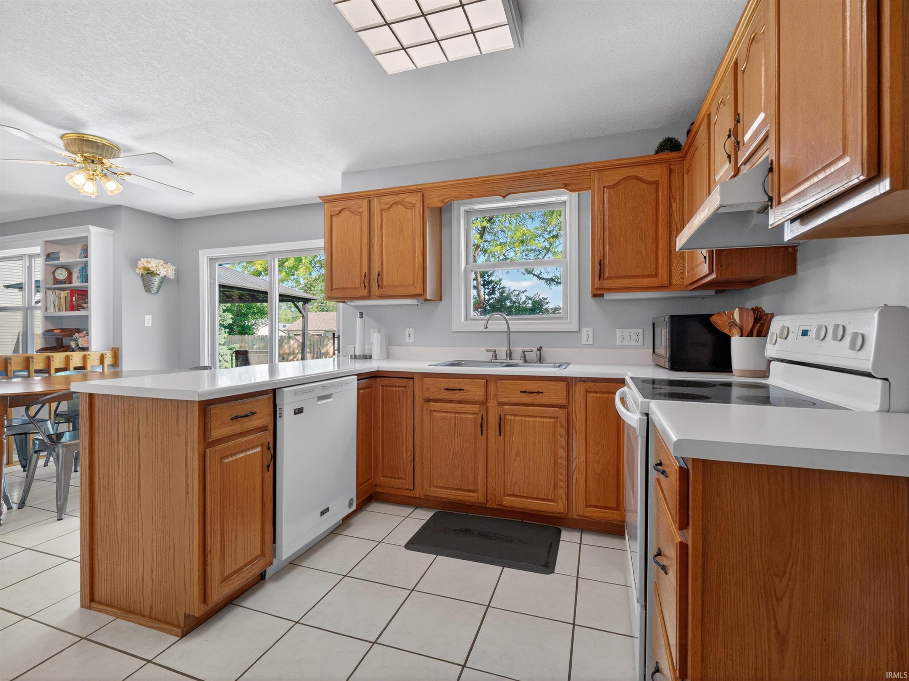 Kitchen featuring wood-finish cabinetry, white countertops, and white tile flooring