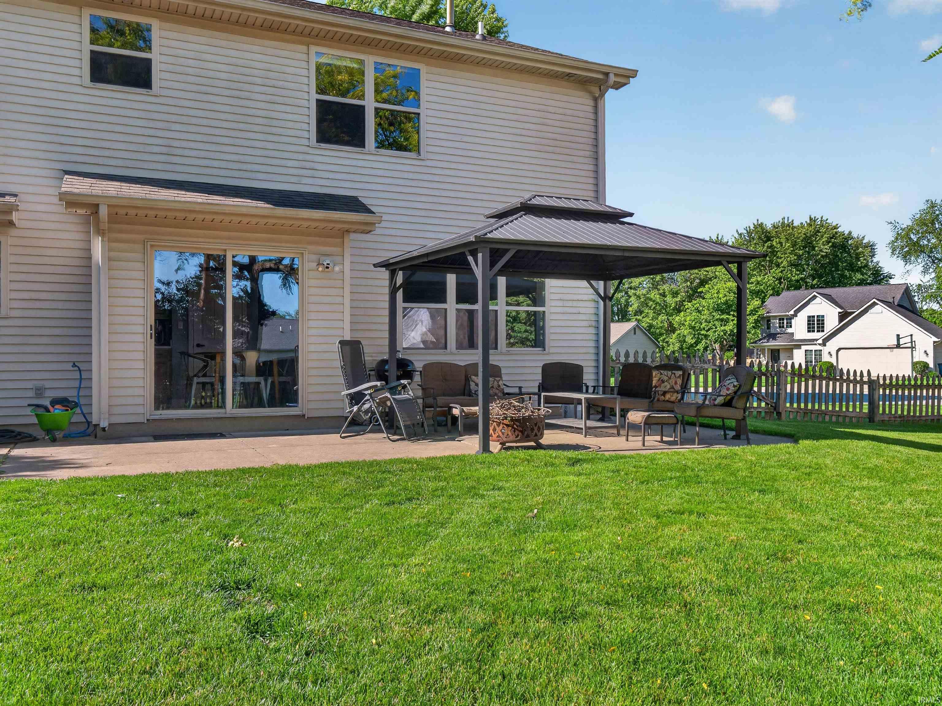Expansive backyard featuring a manicured lawn, a large concrete patio, and a dedicated covered outdoor area