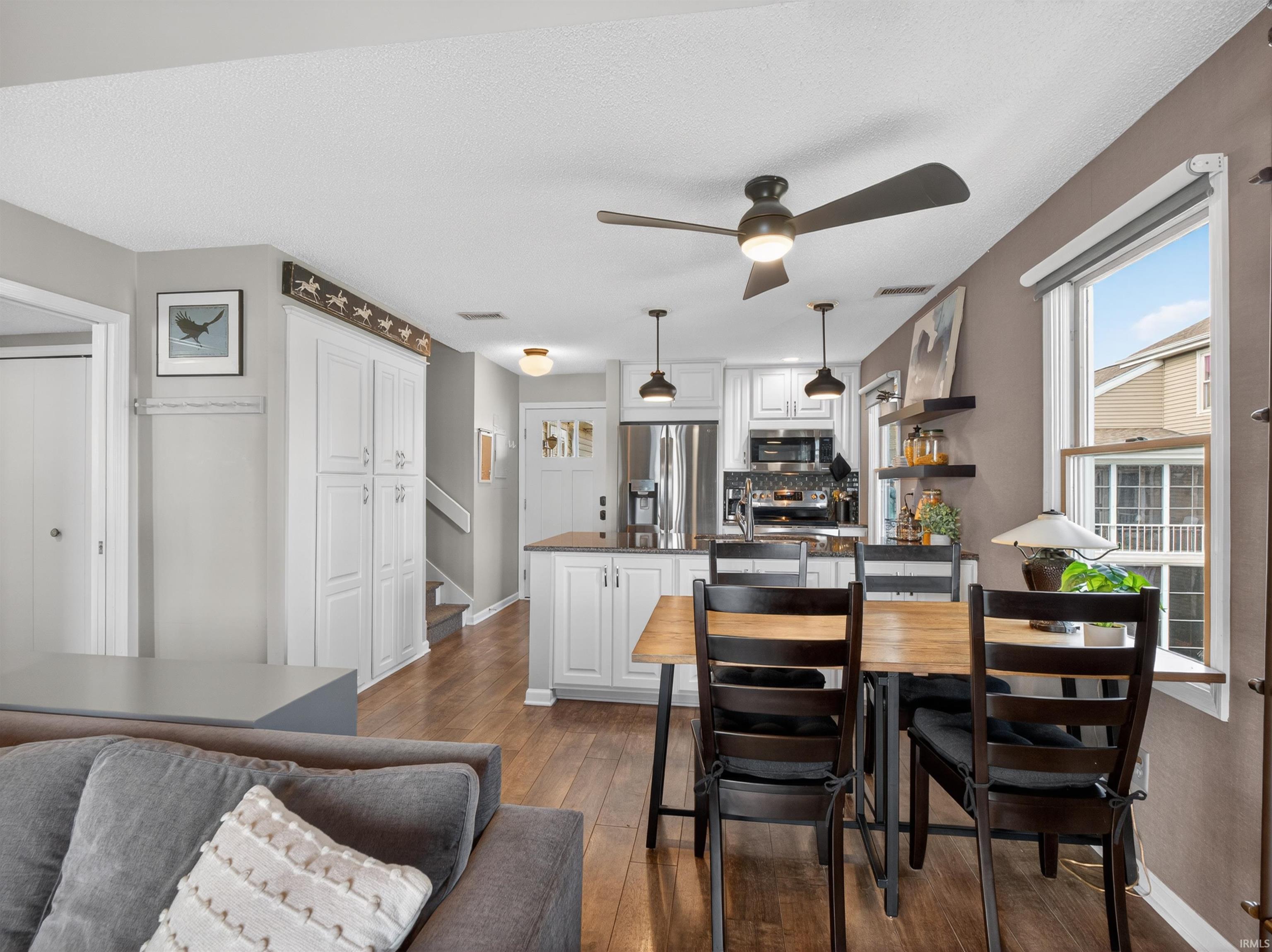 Open-concept living space with wood-finish flooring, a contemporary ceiling fan, and built-in white cabinetry
