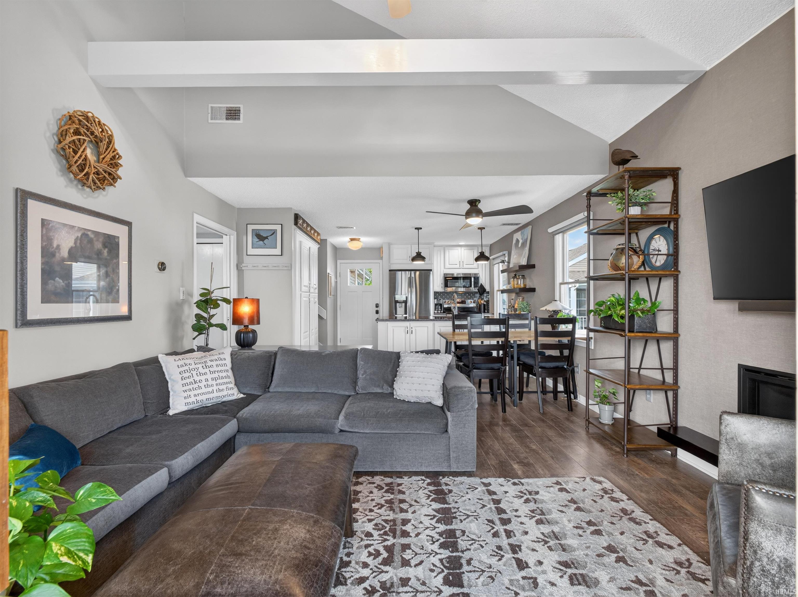 Living space featuring vaulted ceilings with exposed beams, wood-finish flooring, and an open concept layout