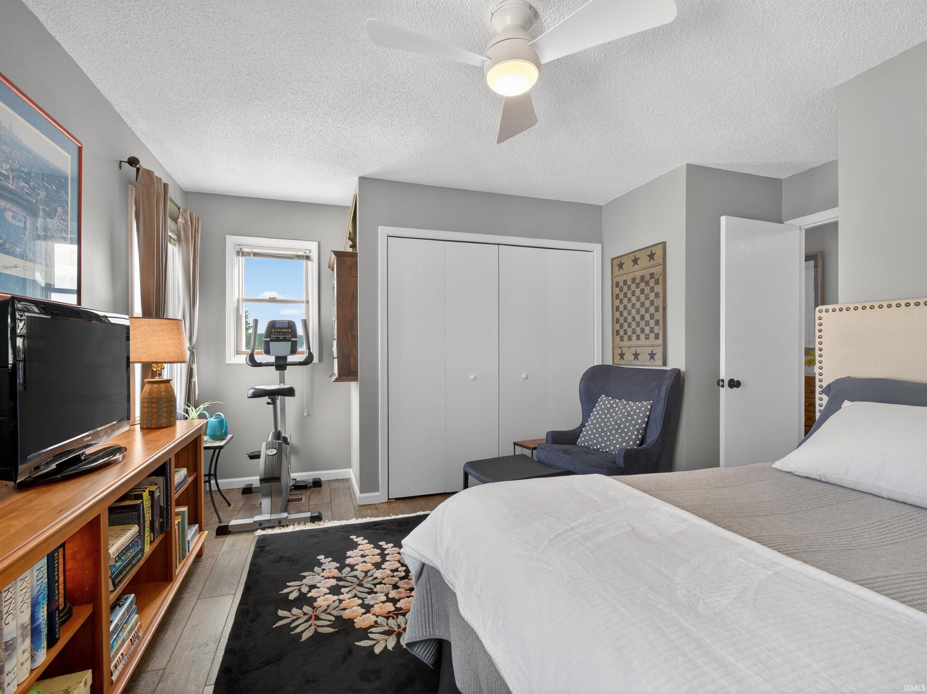 This room features wood-finish flooring, a ceiling fan with integrated lighting, and a window with natural light