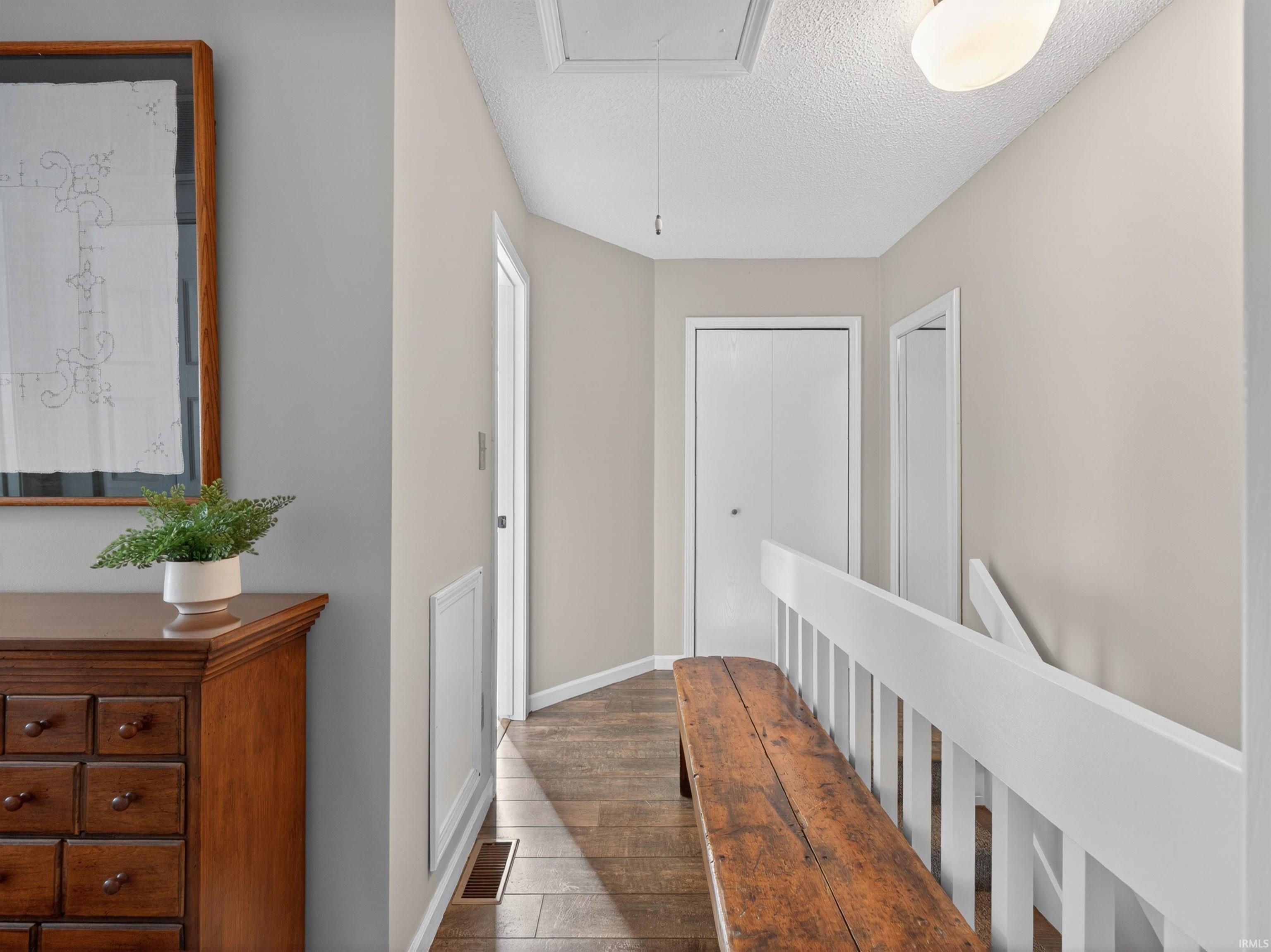 Hallway featuring wood-finish flooring, light neutral wall paint, and white trim