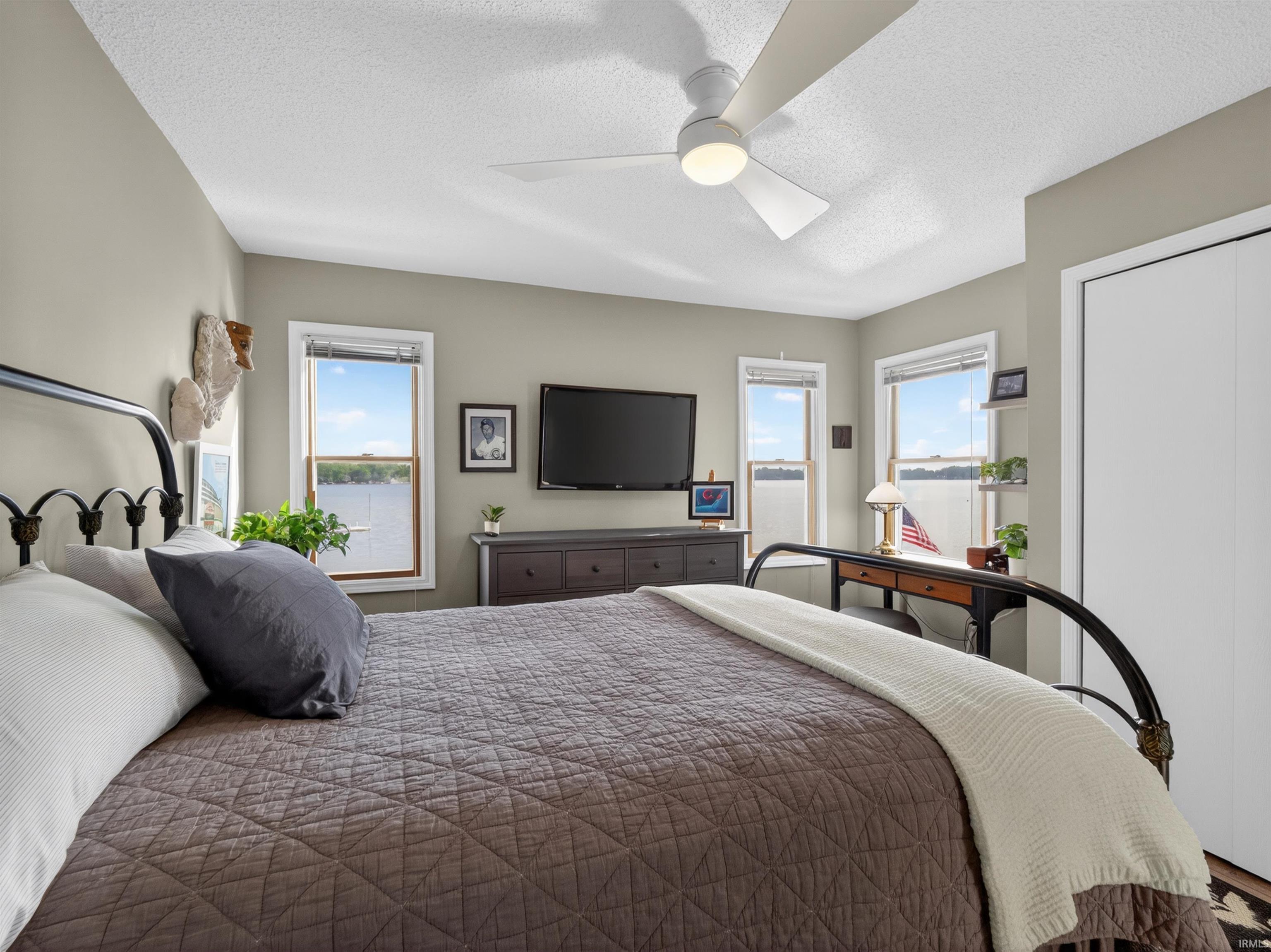 Spacious room featuring multiple windows, a ceiling fan with integrated lighting, two-panel closet doors, and light neutral wall colors