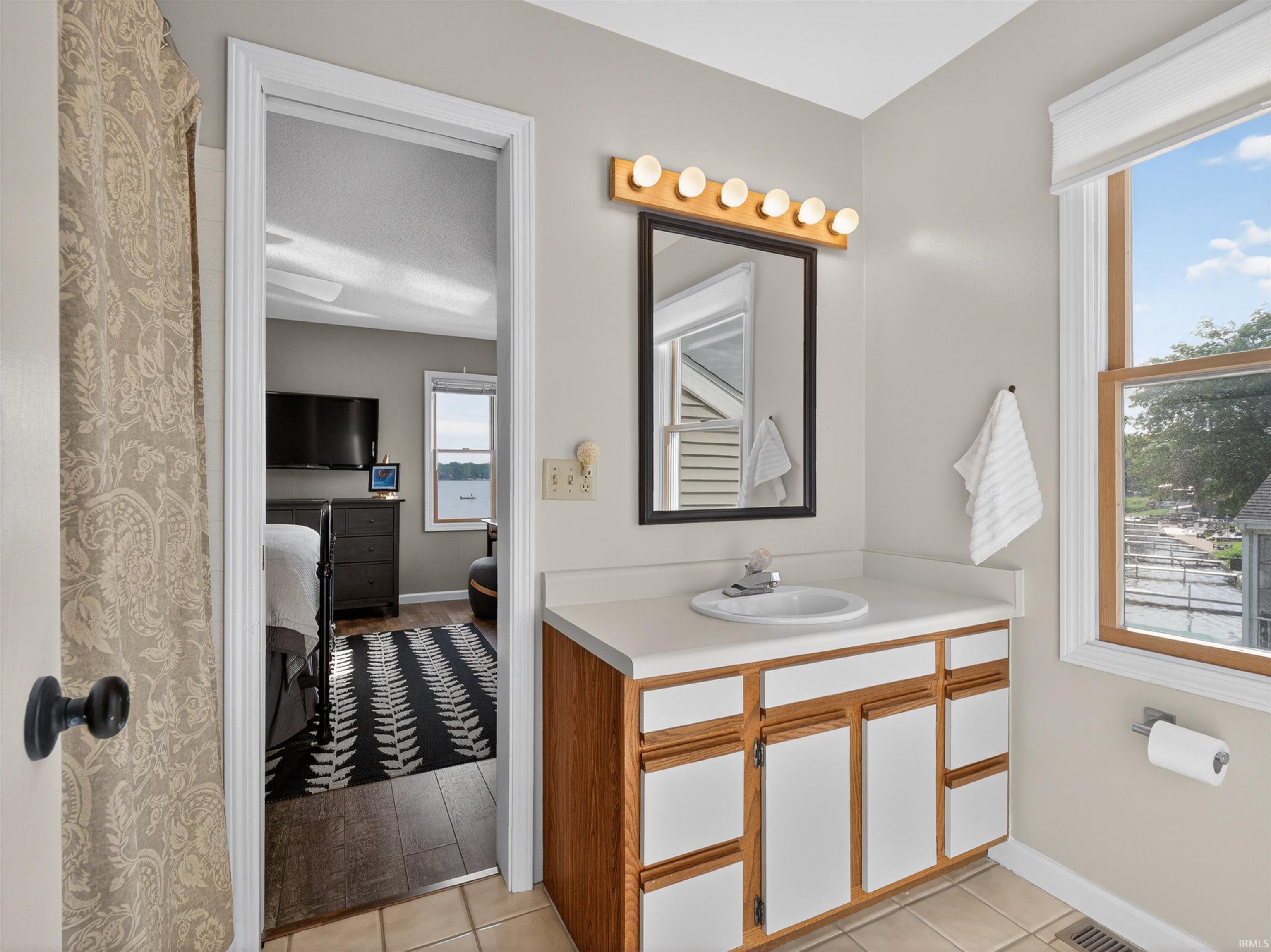 Bathroom vanity with an integrated sink, natural wood-finish cabinetry, and a framed mirror