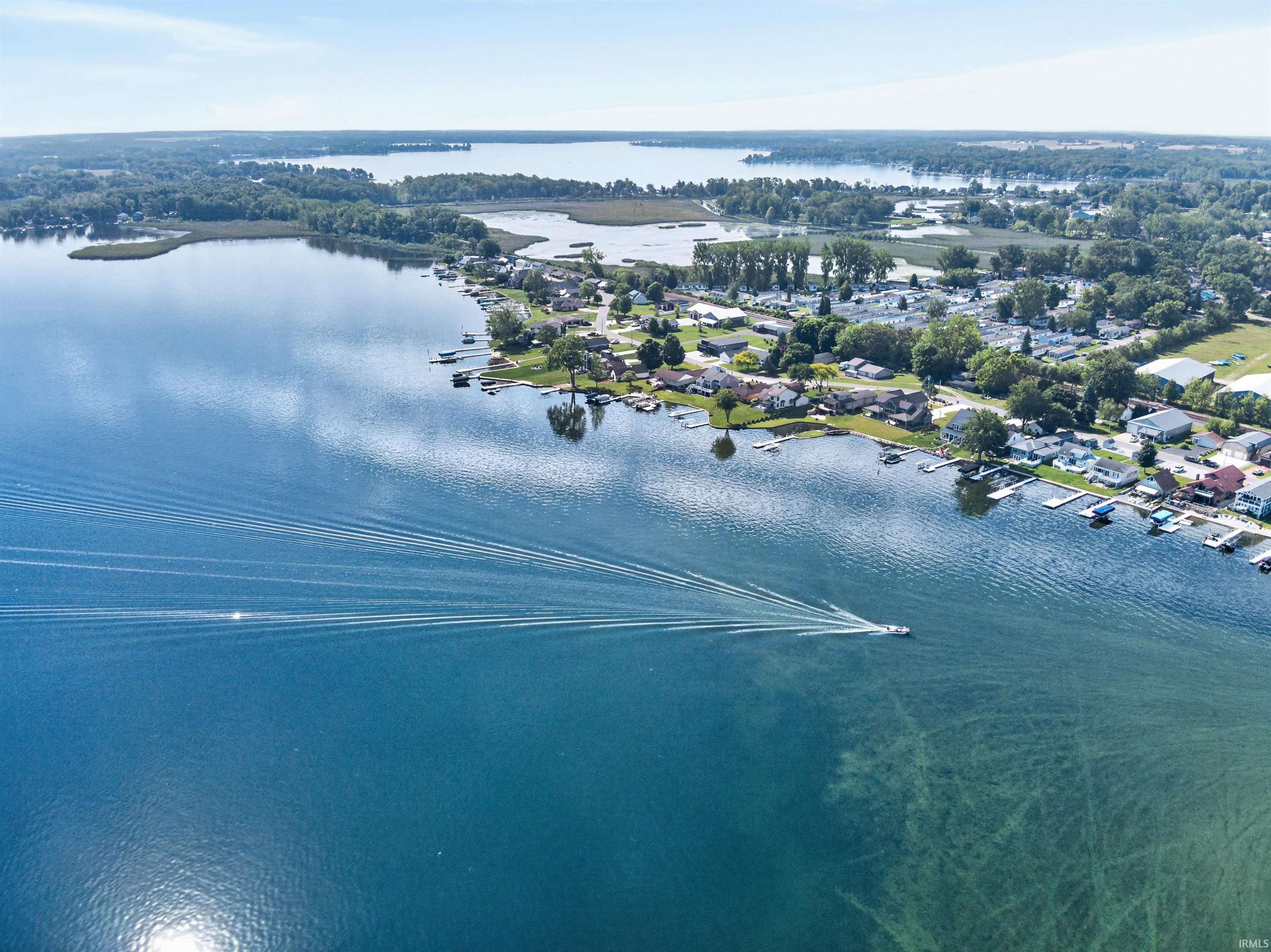 Aerial perspective showcasing a broad body of water with a distinct shoreline featuring residential properties and private docks
