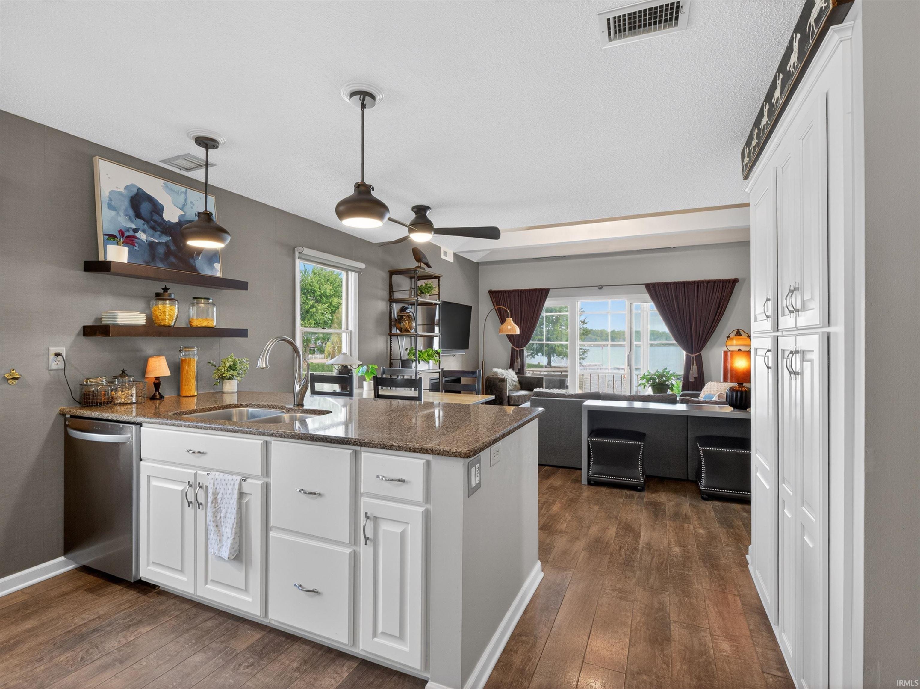 Kitchen island featuring a stainless steel sink with a high-arc faucet, granite-finish countertop, and white cabinetry