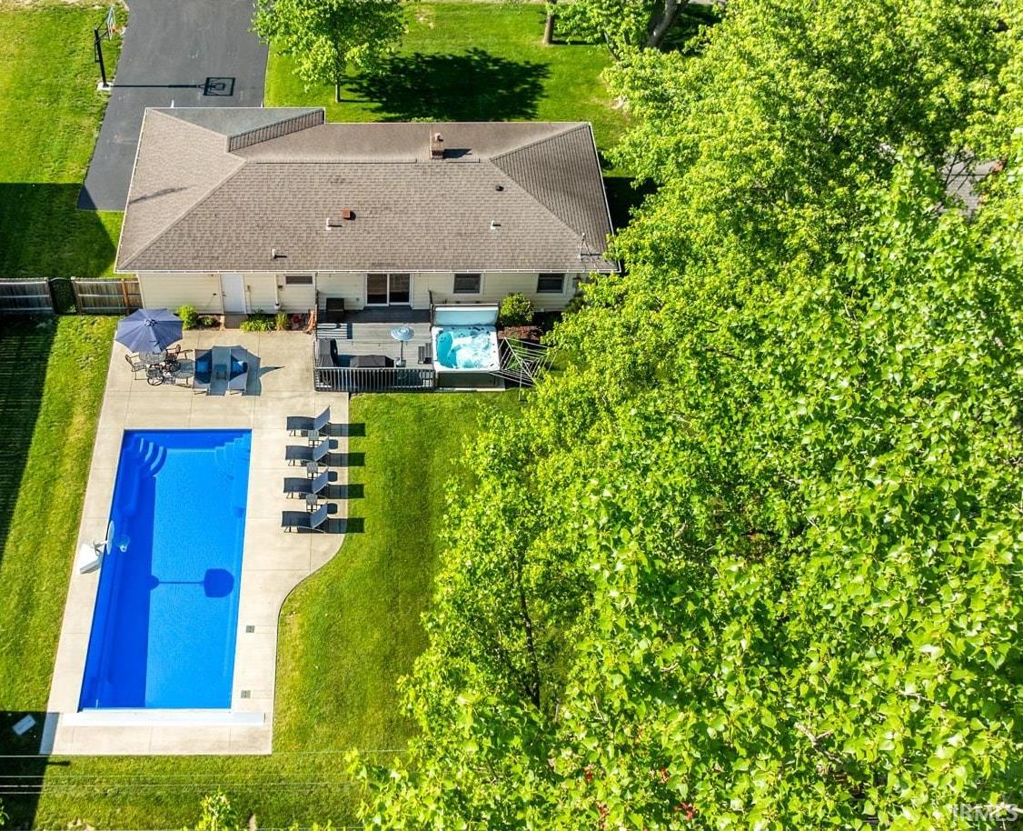 Expansive backyard featuring a rectangular swimming pool with surrounding concrete patio, a built-in spa, and a grassy lawn