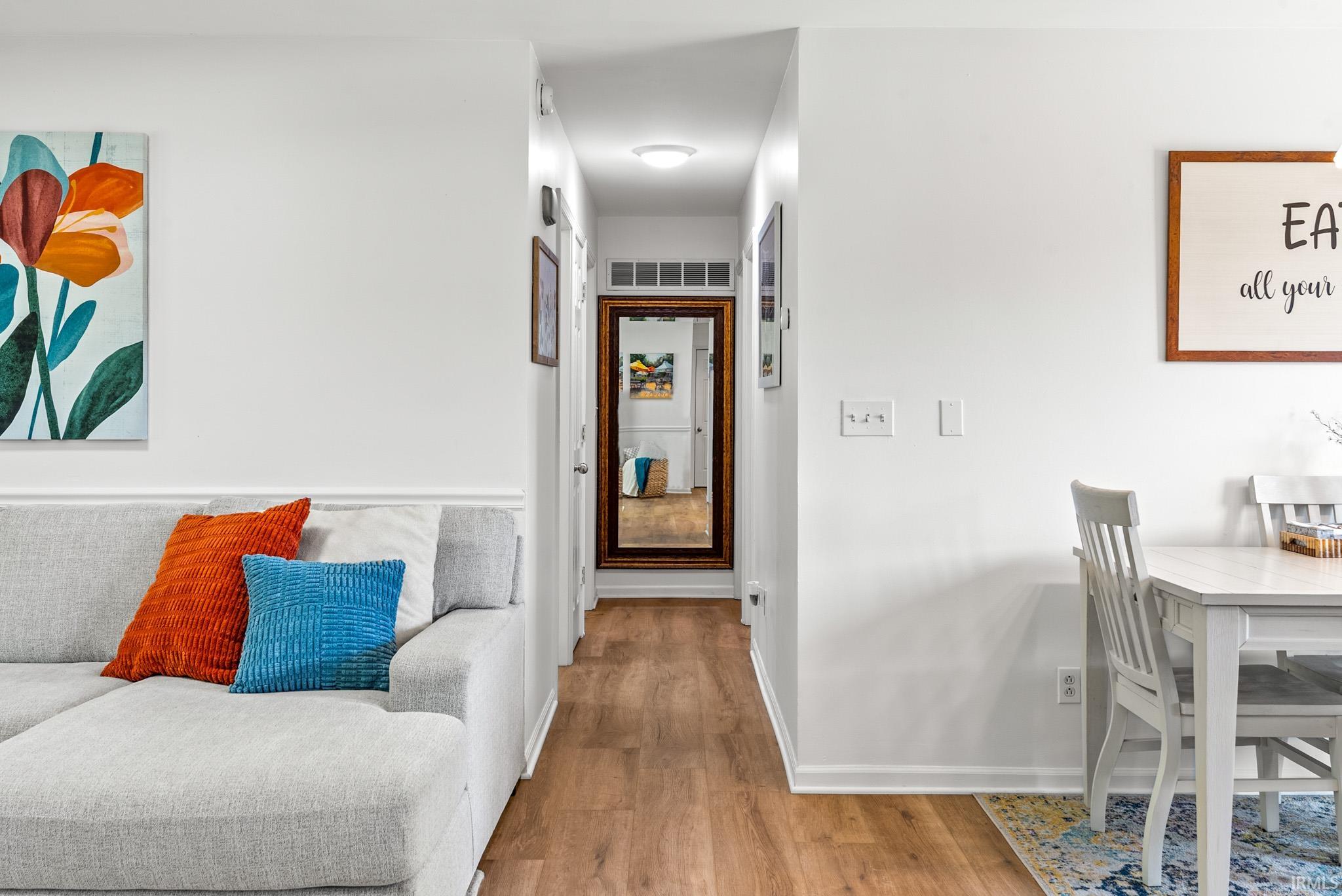 Hallway with wood-finish flooring, white walls, and a full-length mirror
