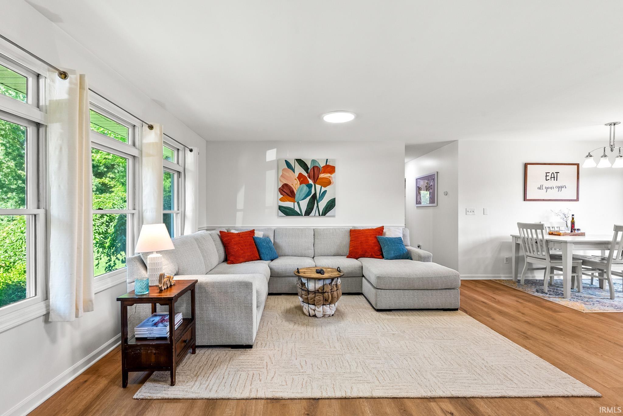 Spacious living area featuring expansive windows, wood-finish flooring, recessed lighting, and a neutral color palette