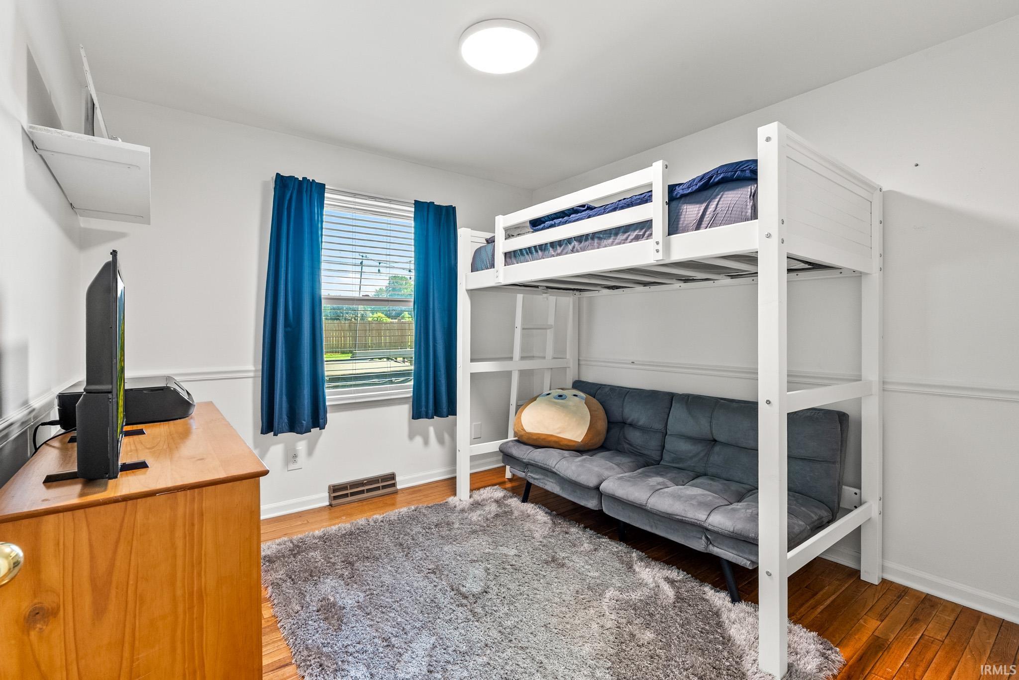 Bright room featuring wood-finish flooring and white walls with wainscoting