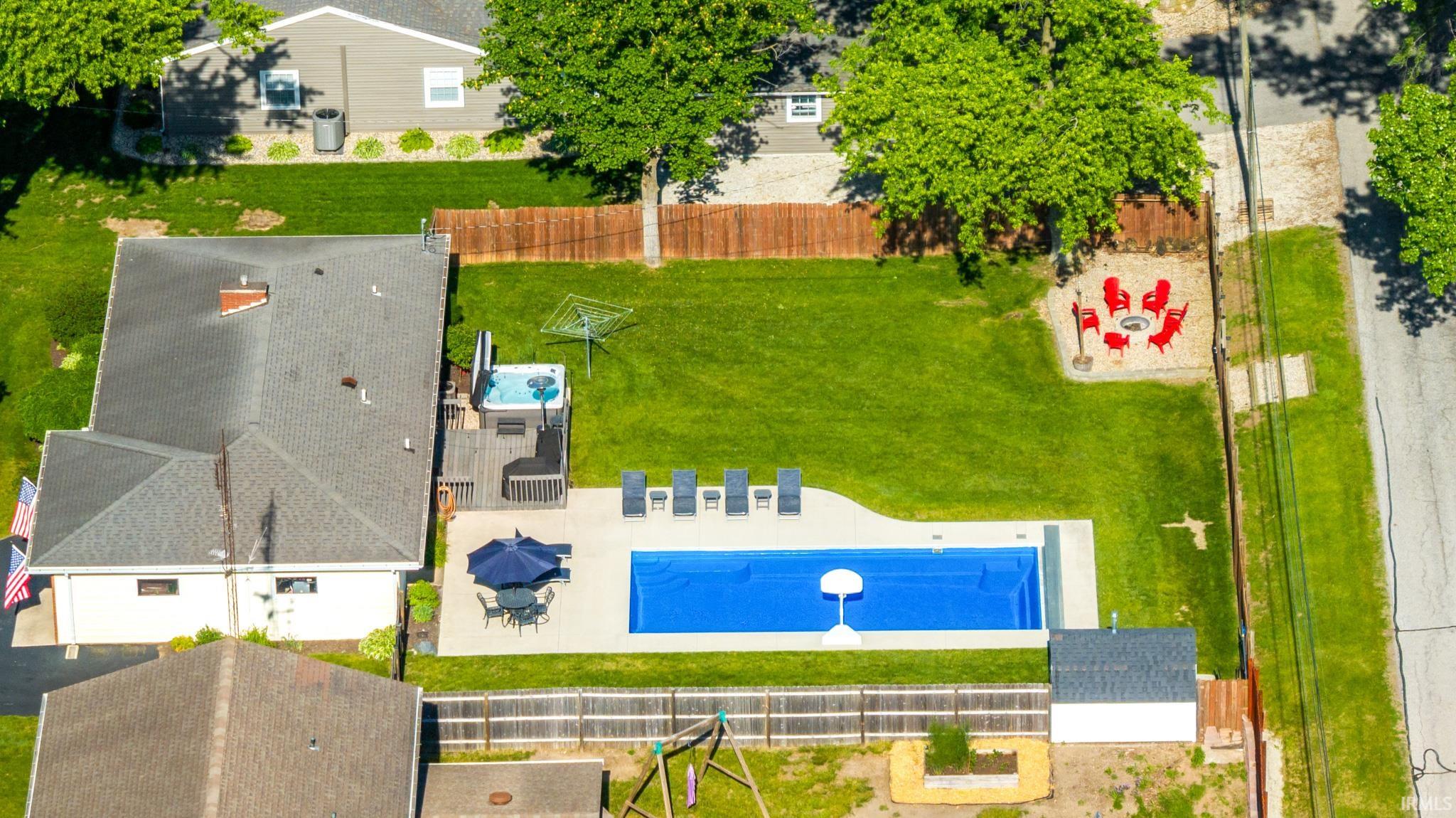Expansive backyard featuring a rectangular swimming pool, spacious pool deck, and a hot tub on an elevated wood deck