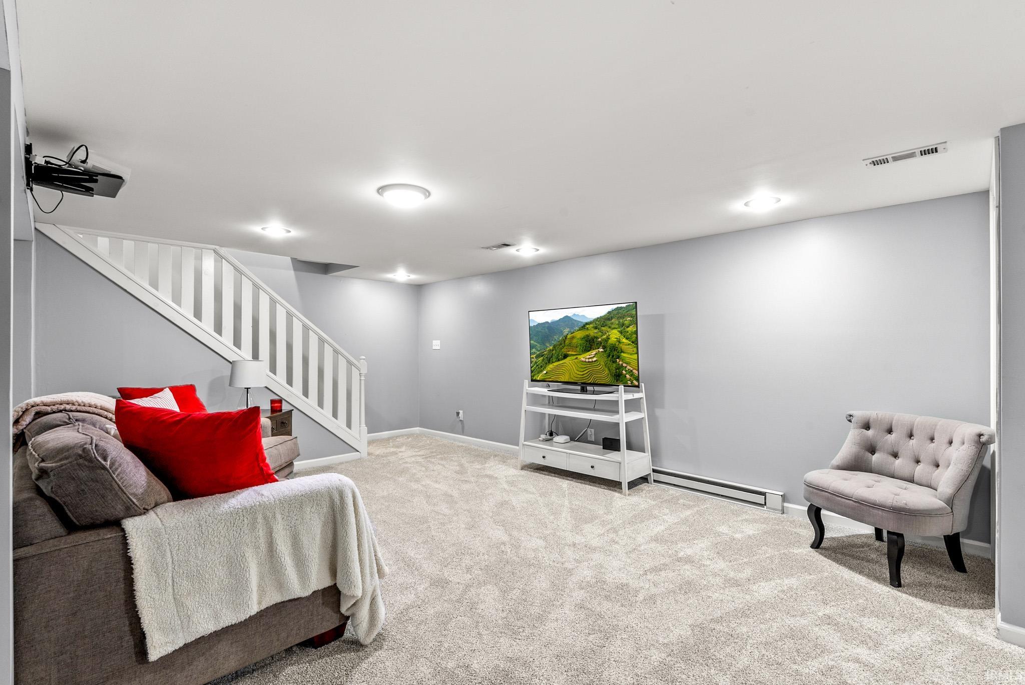 Spacious room featuring light gray walls, recessed lighting, and soft gray carpeting