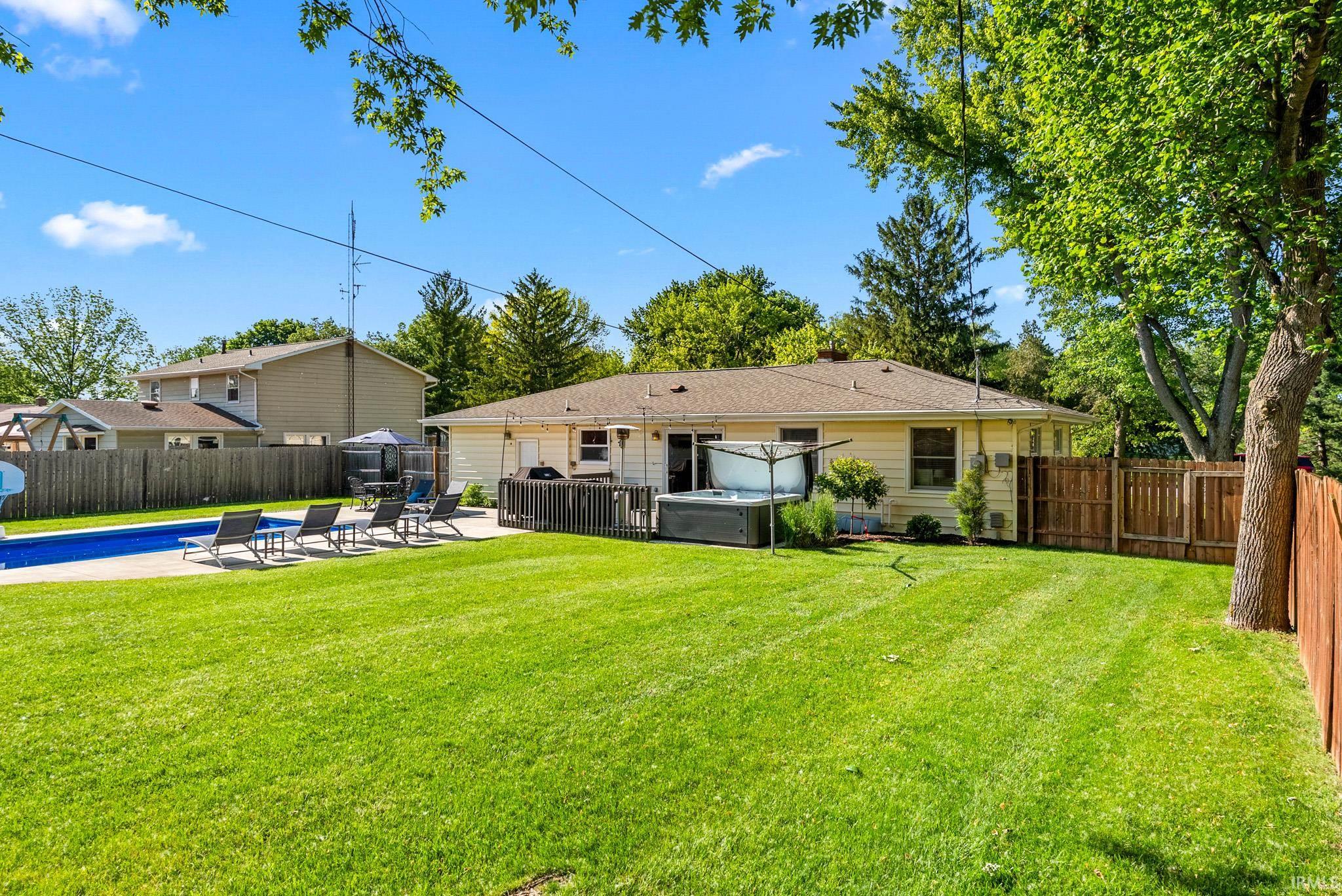 Expansive green lawn with an in-ground swimming pool, surrounded by a concrete patio