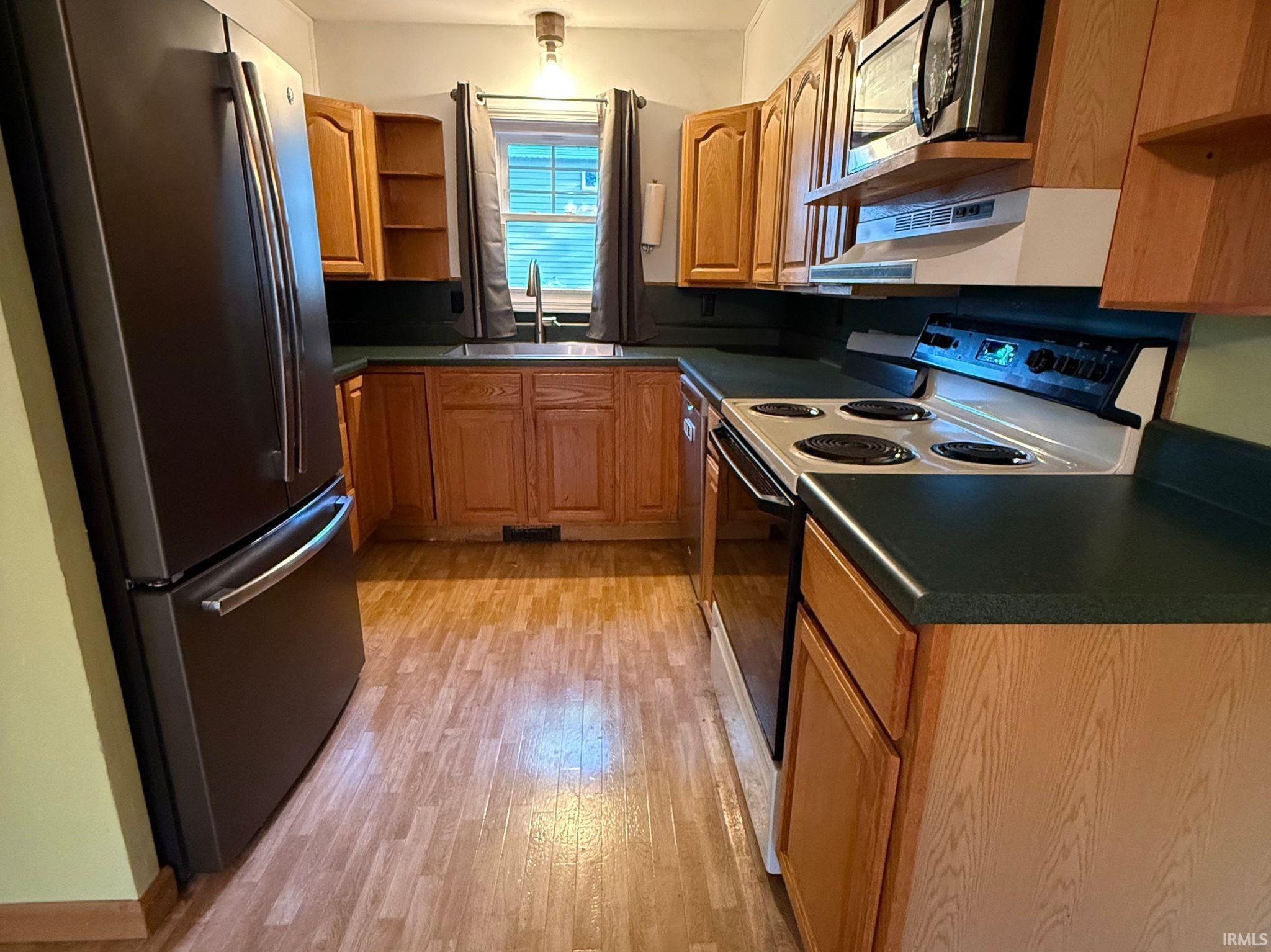 Kitchen featuring wood-finish flooring, dark countertops, and light wood cabinetry